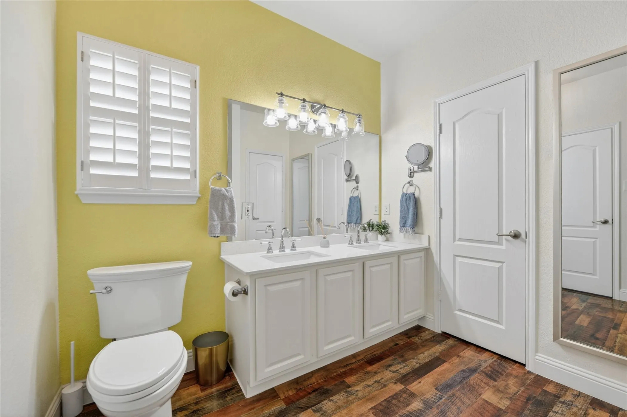 Dual vanity with white cabinetry and integrated sinks, under a broad mirror and sconce lighting
