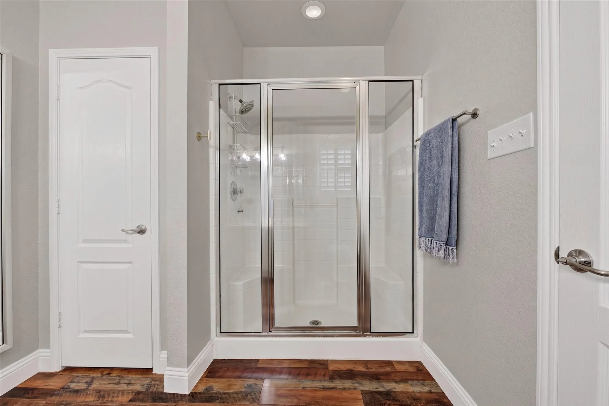 Glass-enclosed shower with a built-in bench and chrome fixtures