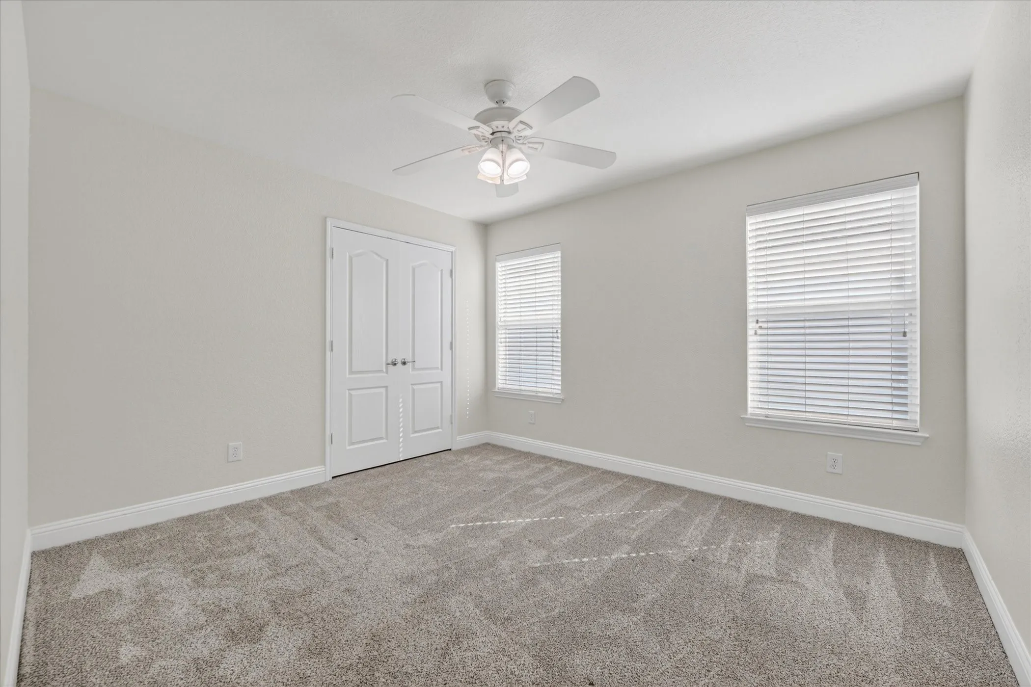 Bedroom Three Spacious room featuring neutral carpeting, a ceiling fan with integrated lighting, and two windows with blinds