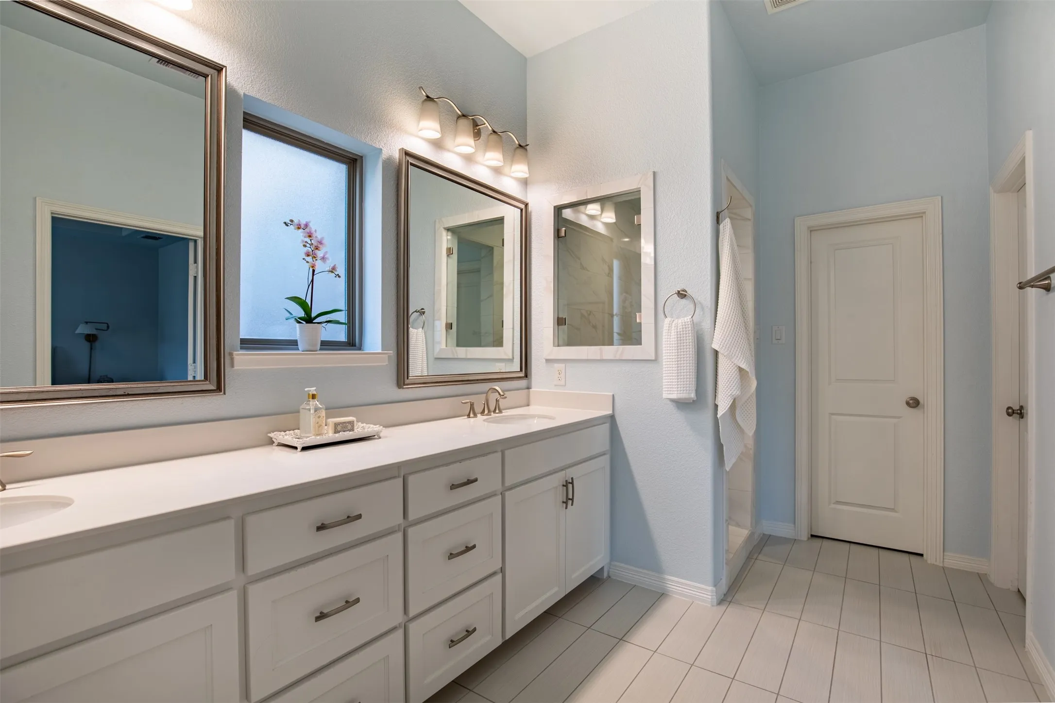 Walk in Shower. Double vanity featuring white cabinetry and quartz countertops.