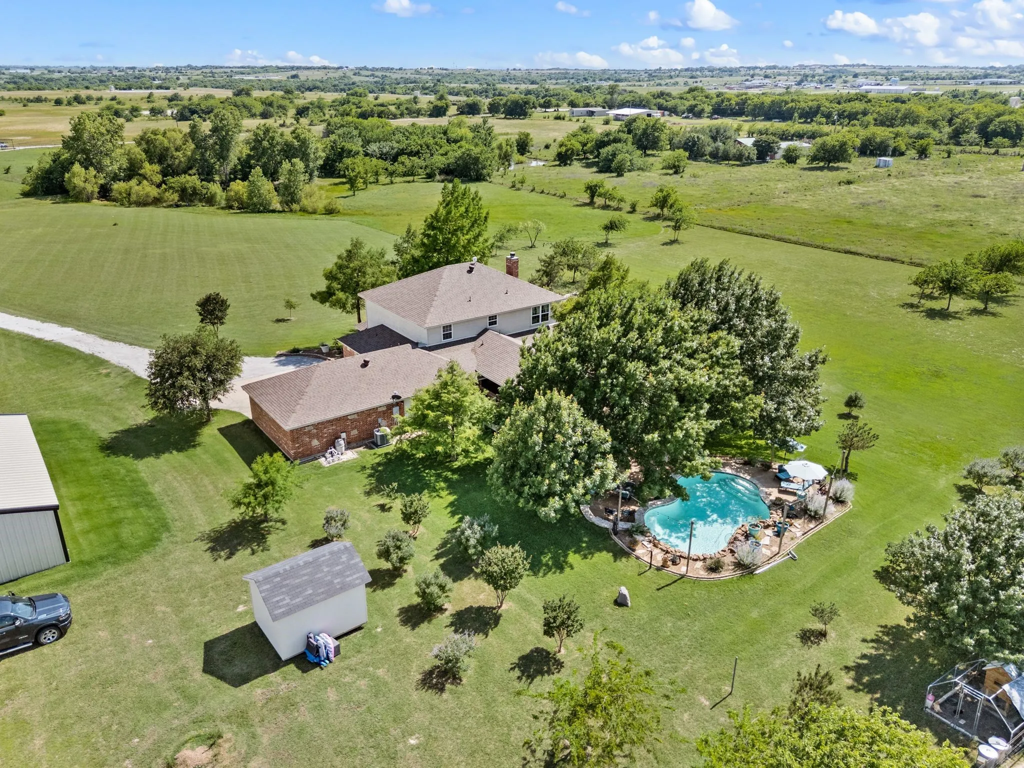 Aerial view of property featuring residen, a freeform swimming pool, a metal building, a storage shed.