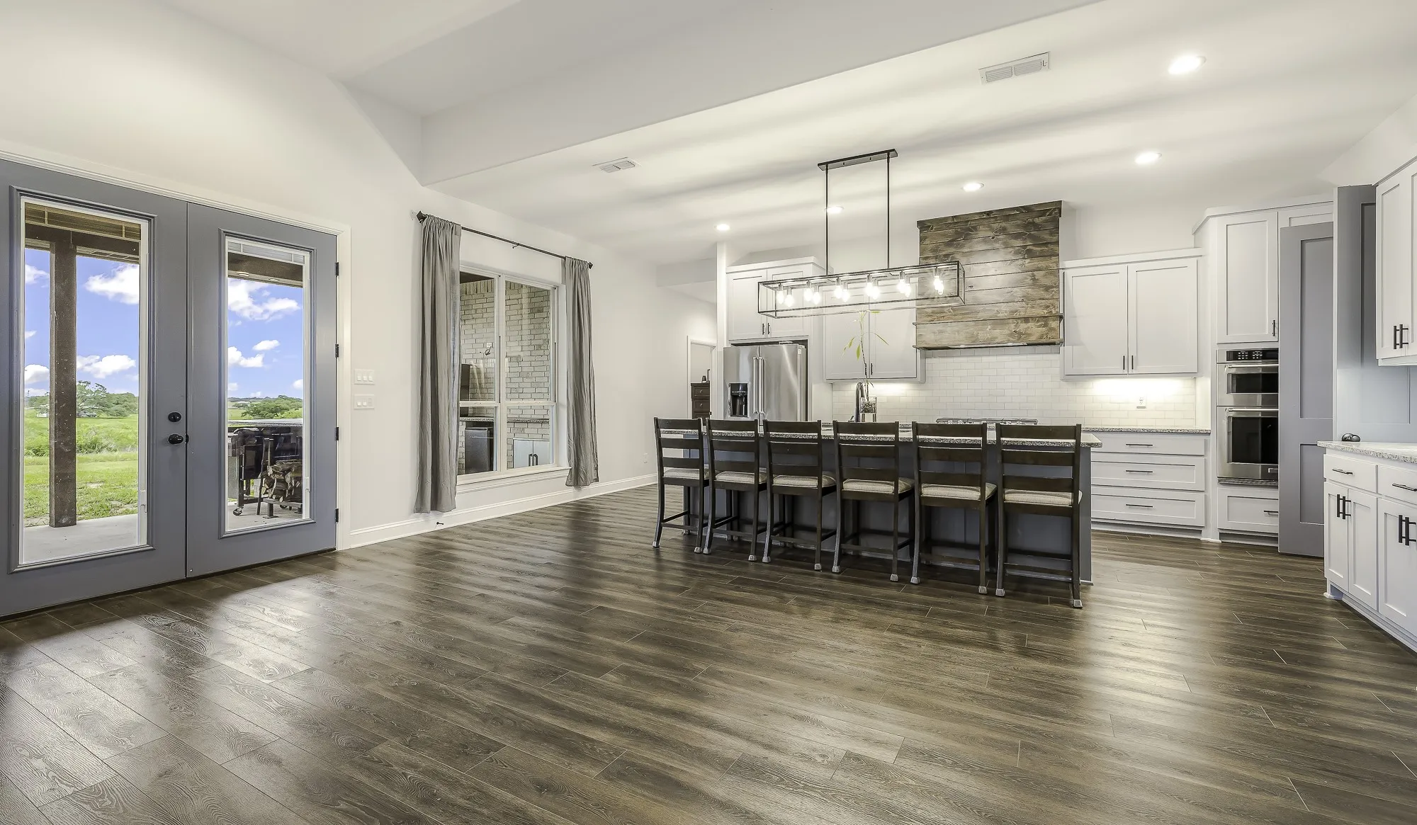 Open-concept kitchen and living area featuring wood-finish flooring, vaulted ceilings, and recessed lighting