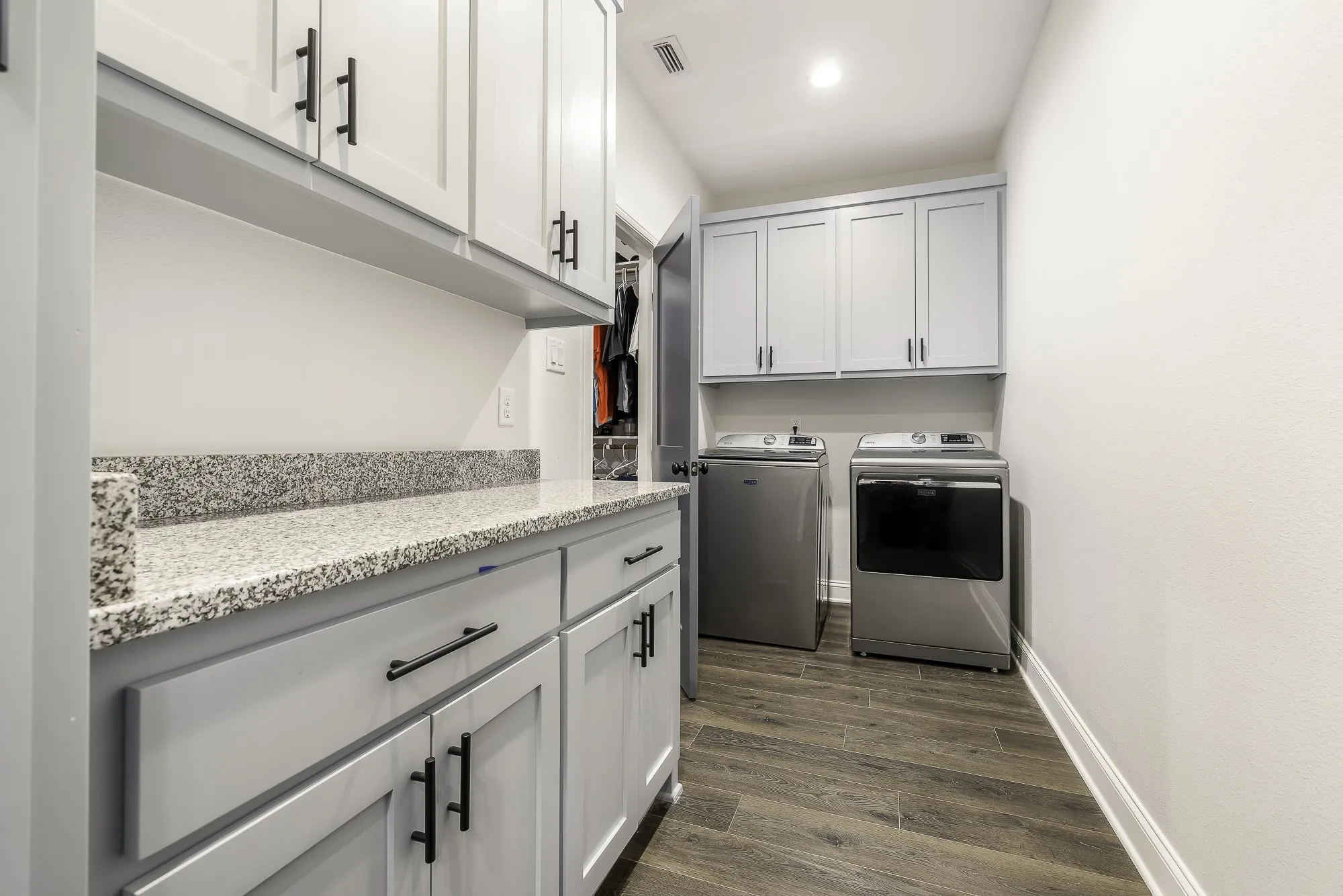Laundry area featuring light gray cabinetry, granite countertops, wood-finish flooring, recessed lighting, and wall-mounted upper storage