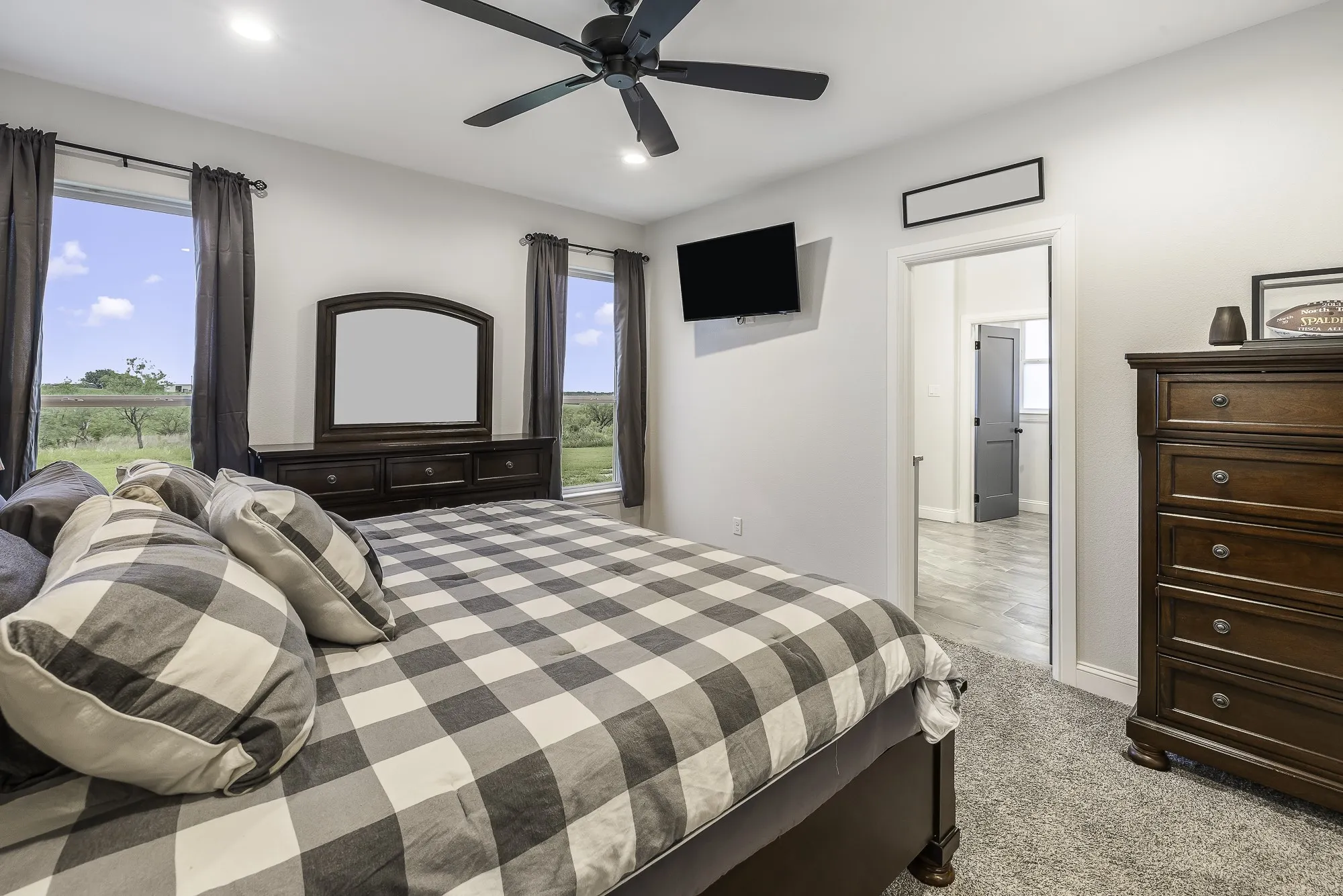 Neutral color palette bedroom featuring two windows, carpet flooring, a ceiling fan with integrated lighting, and recessed ceiling lights