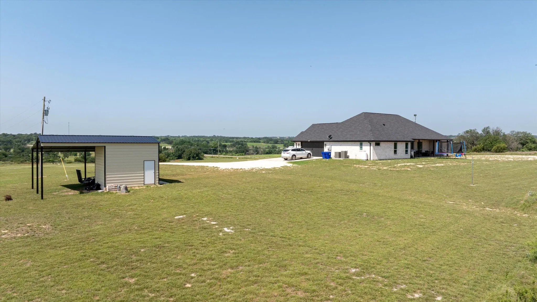 Expansive lot featuring a single-story dwelling with white siding and a dark shingle roof