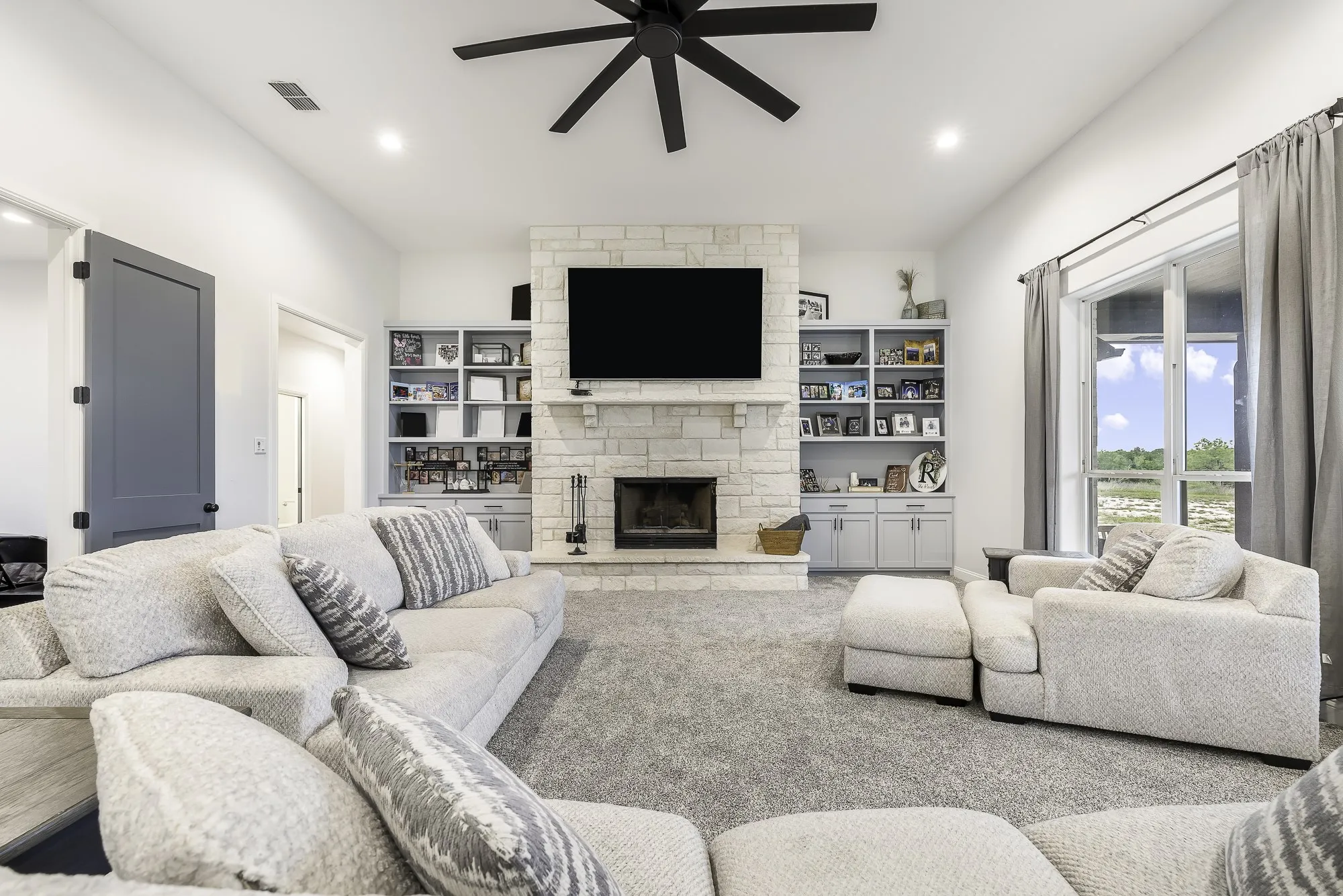 Spacious living area featuring a stone-clad fireplace and built-in shelving