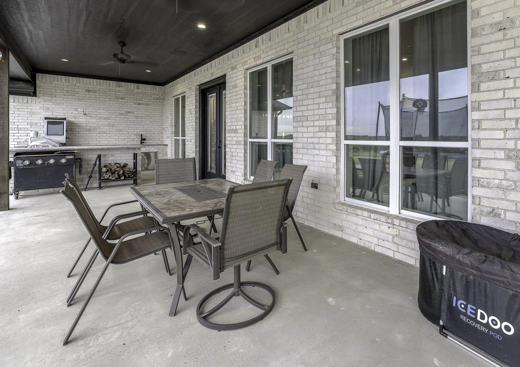 Covered patio featuring a concrete floor, brick exterior, and a built-in outdoor kitchen with a​​‌​​​​‌​​‌‌​‌‌​​​‌‌​‌​‌​‌​​​‌​​ sink