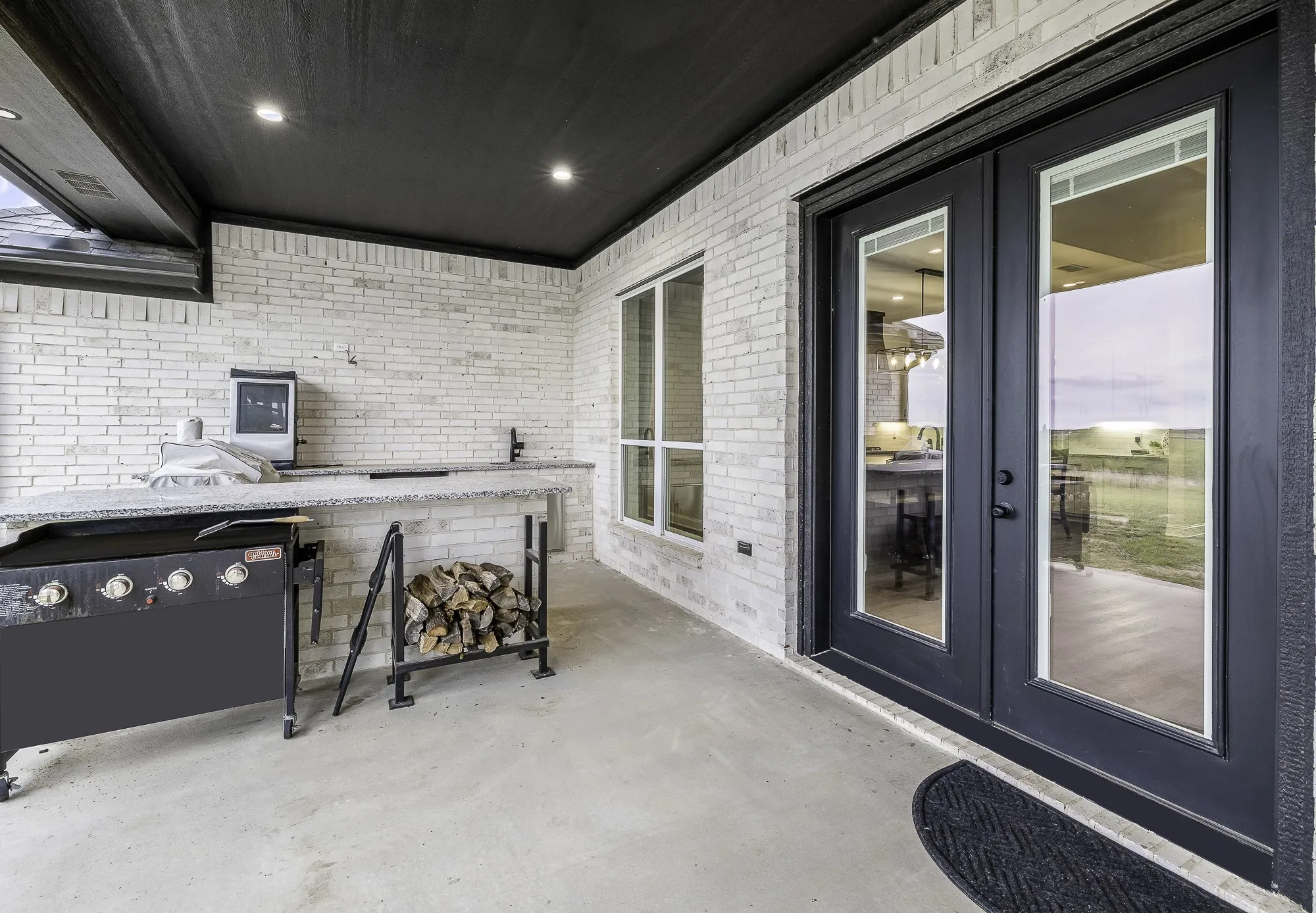 Covered patio with light-toned brick walls and a dark ceiling with recessed lighting
