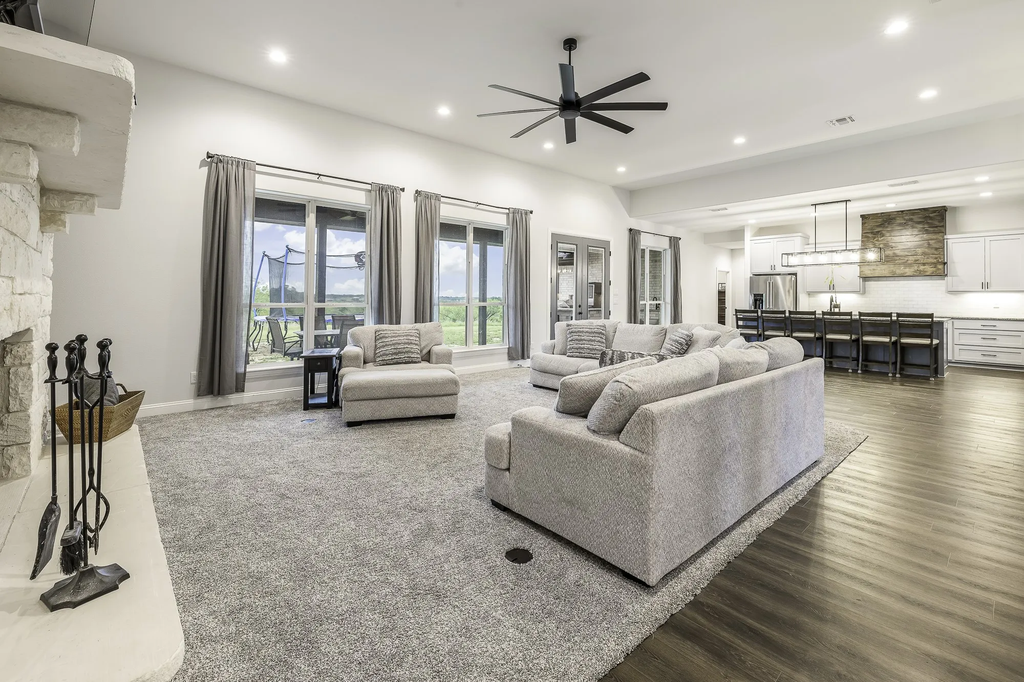 Open-concept living space featuring a stone-clad fireplace and wood-finish flooring
