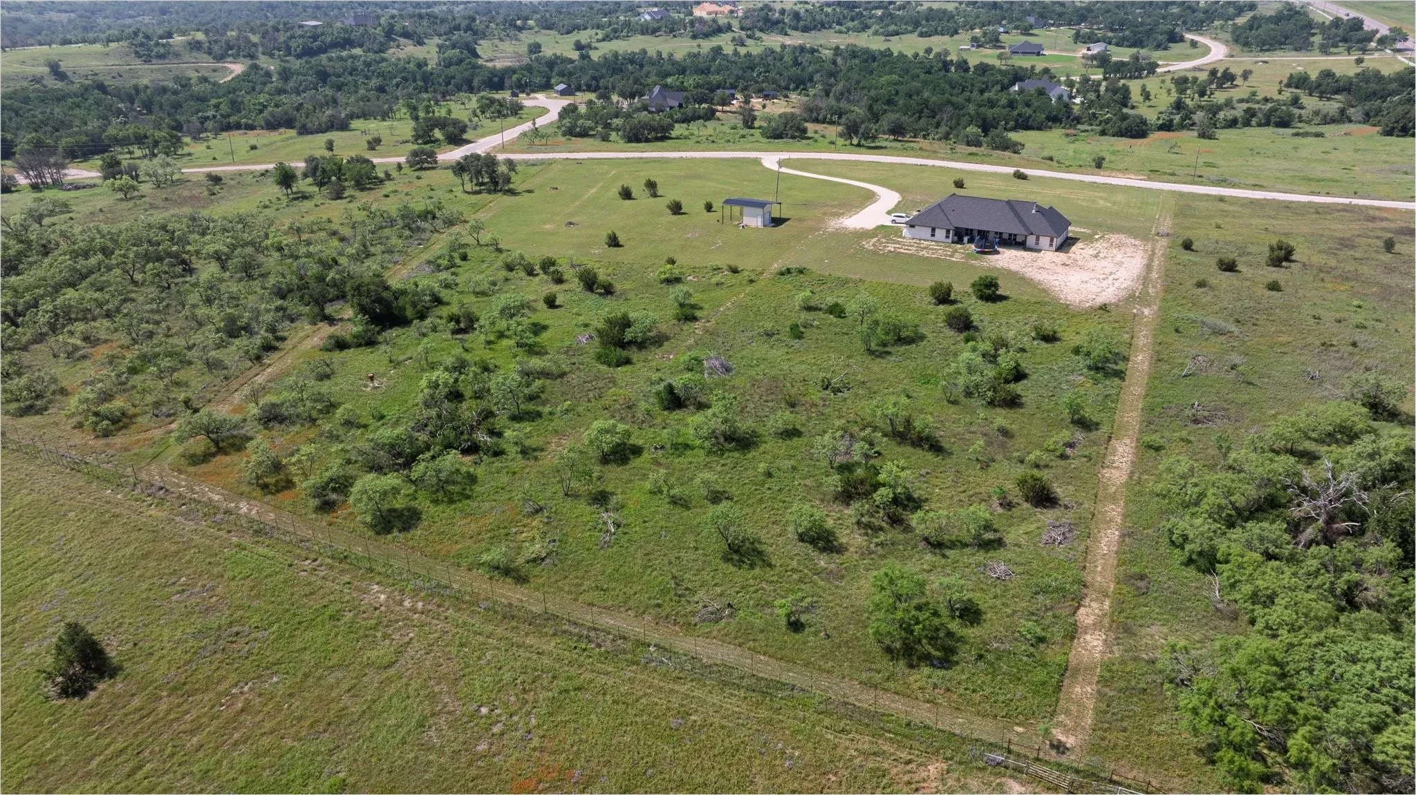 Expansive rural property featuring a single-story residence with a dark roof