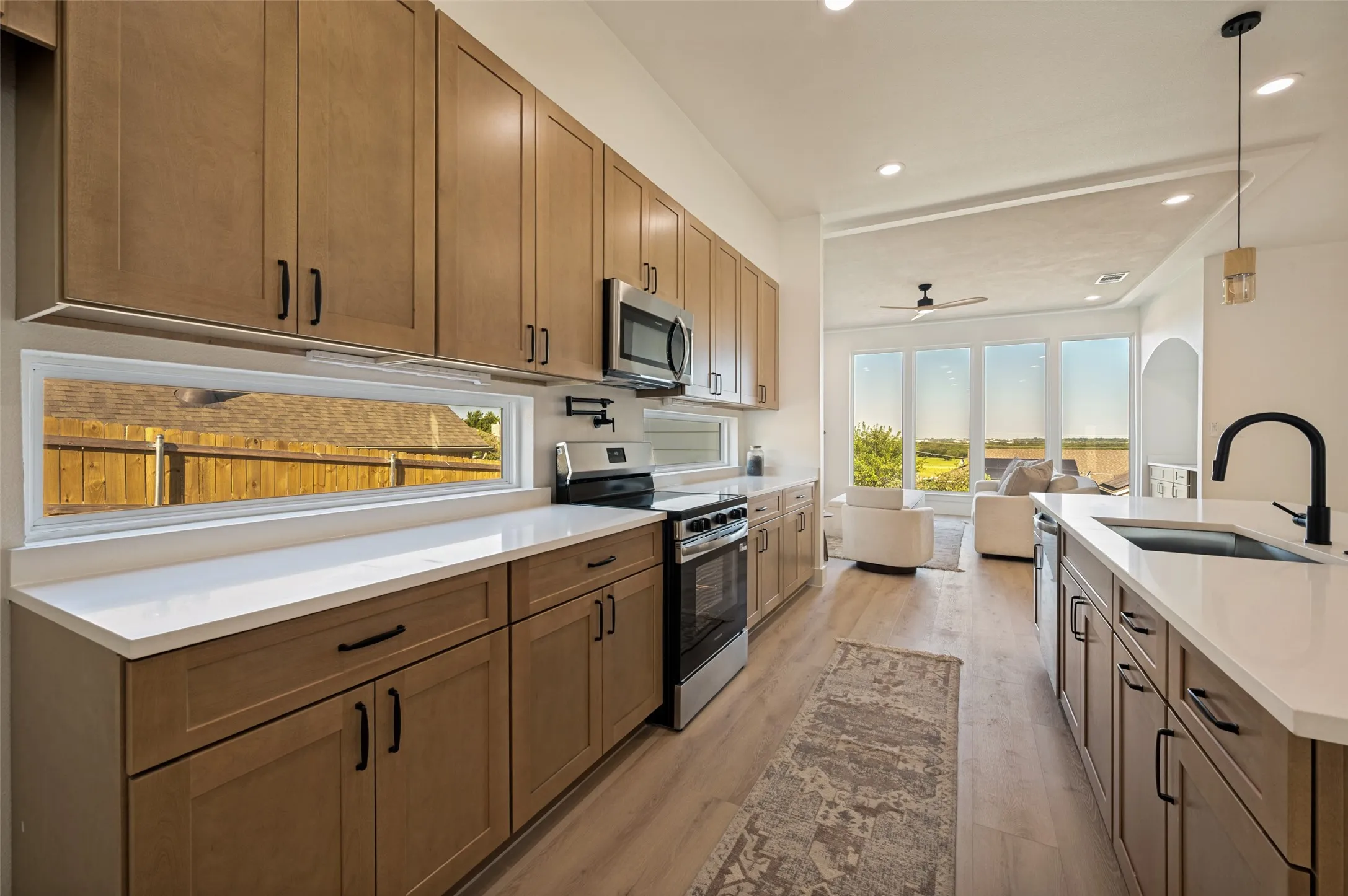 Modern kitchen featuring light wood-finish cabinetry, white countertops, and stainless steel appliances
