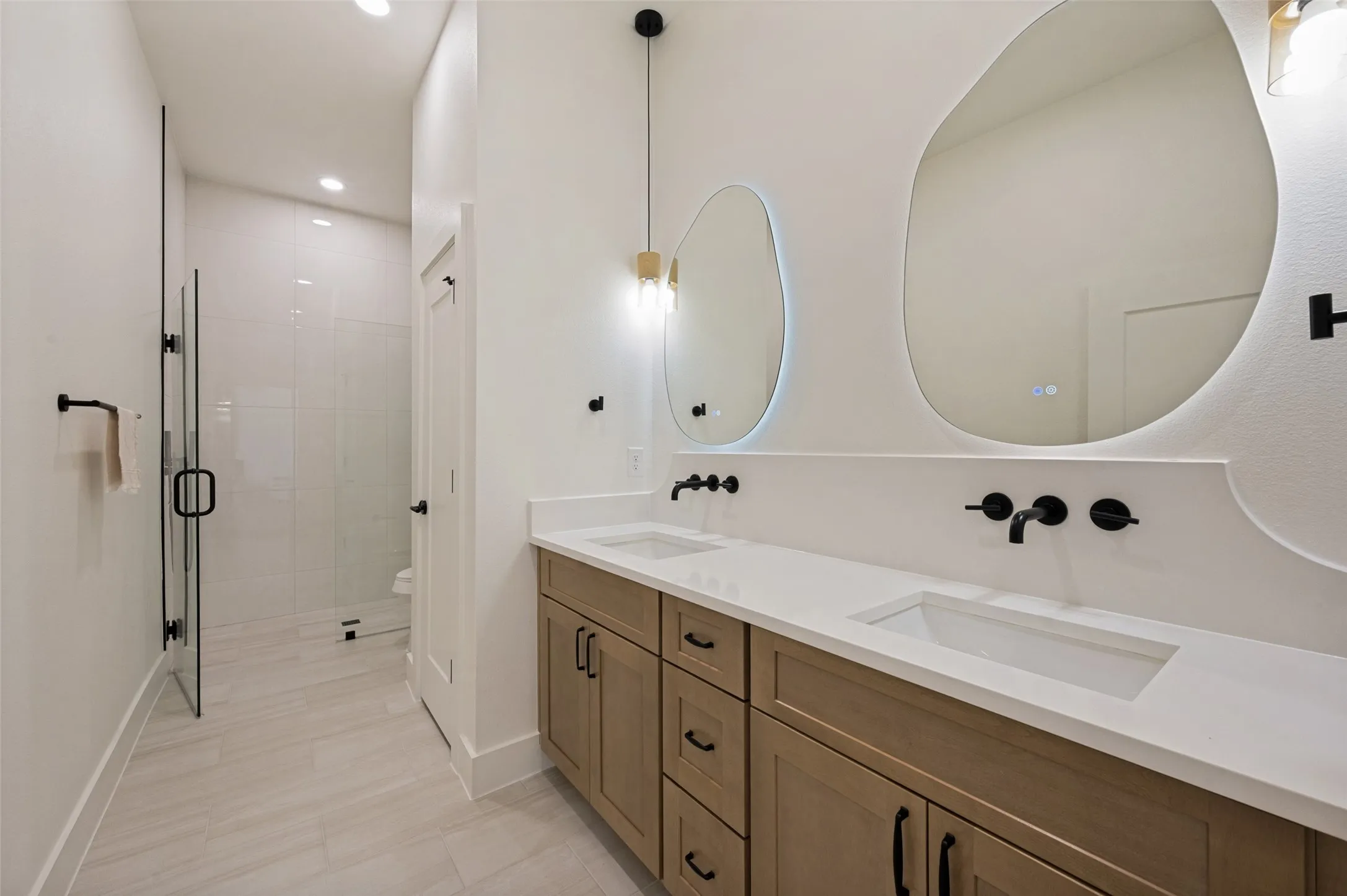 Double vanity with integrated sinks, quartz countertop, and wall-mounted matte black faucets