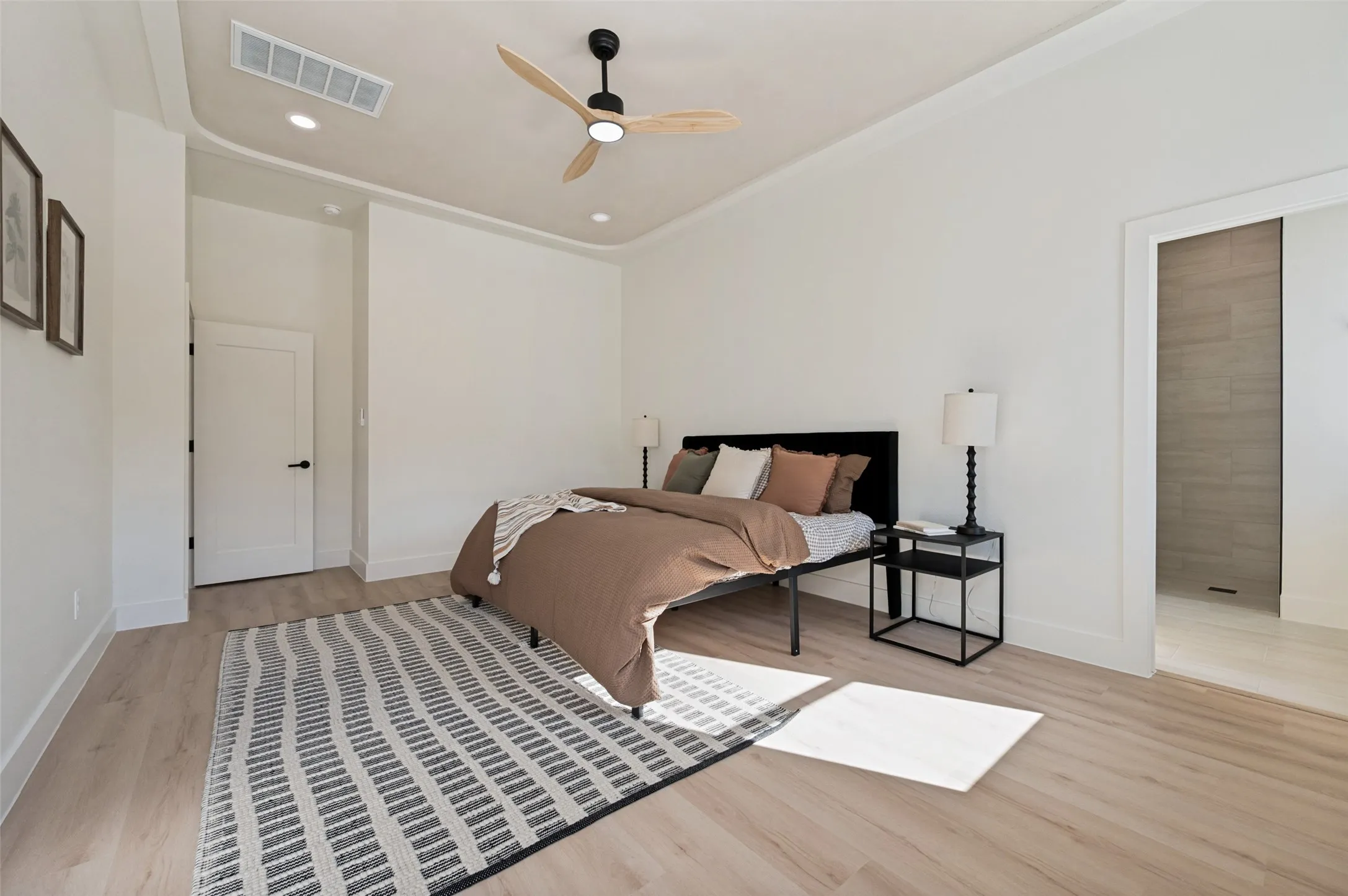 Spacious room featuring light wood-finish flooring, white baseboards, and a contemporary ceiling fan with integrated lighting