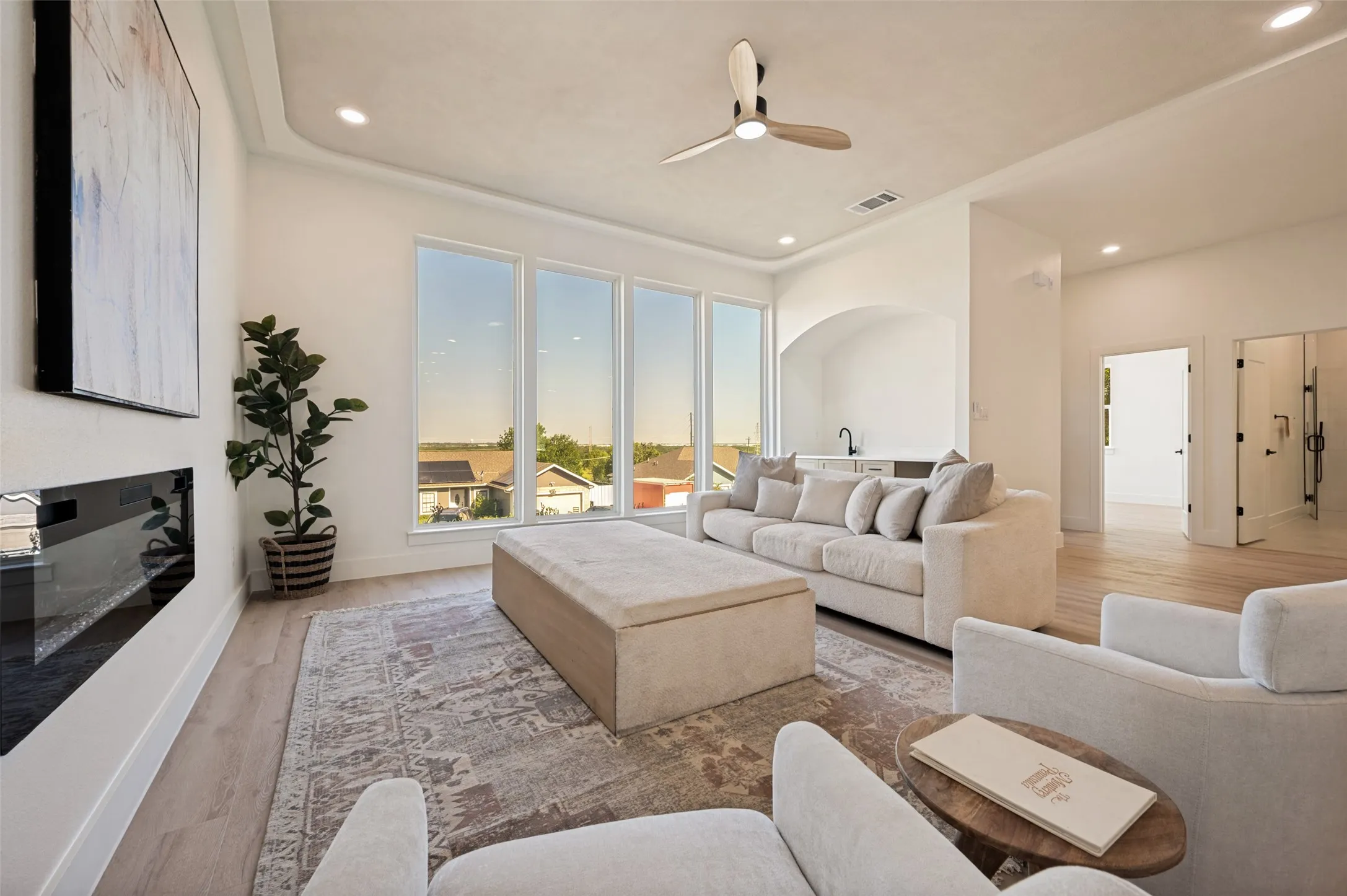 Bright living area featuring large windows, wood-finish flooring, and a built-in linear fireplace