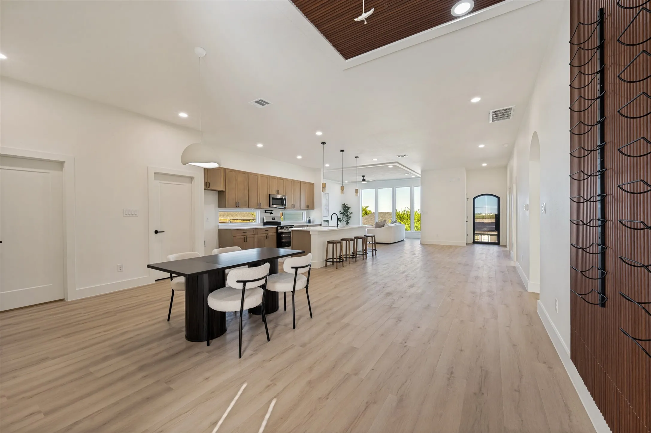Open-concept living space featuring light wood-finish flooring, recessed lighting, and a vaulted ceiling with a wood slat accent