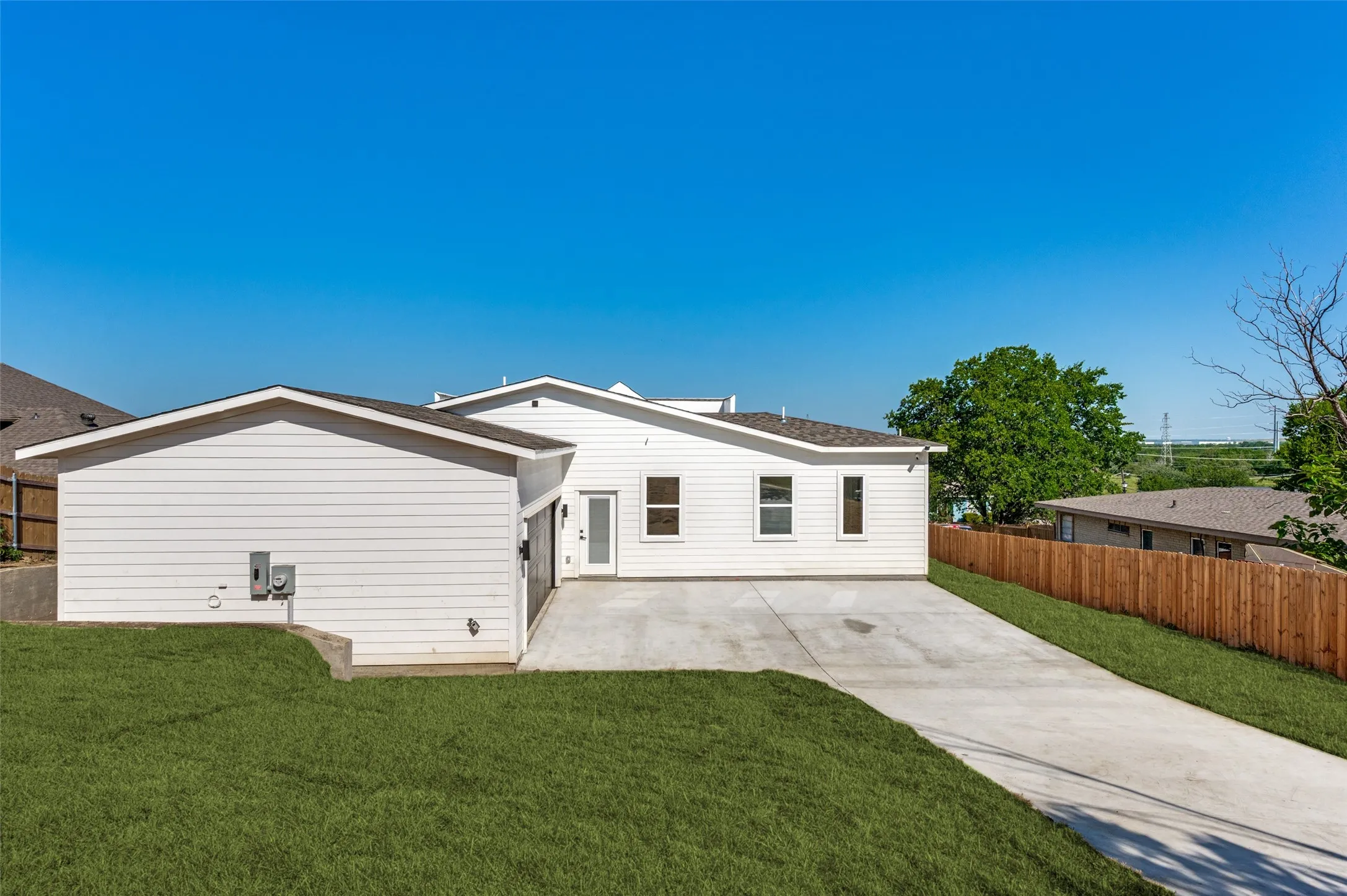 White siding exterior with a concrete driveway, attached garage, and a wood privacy fence