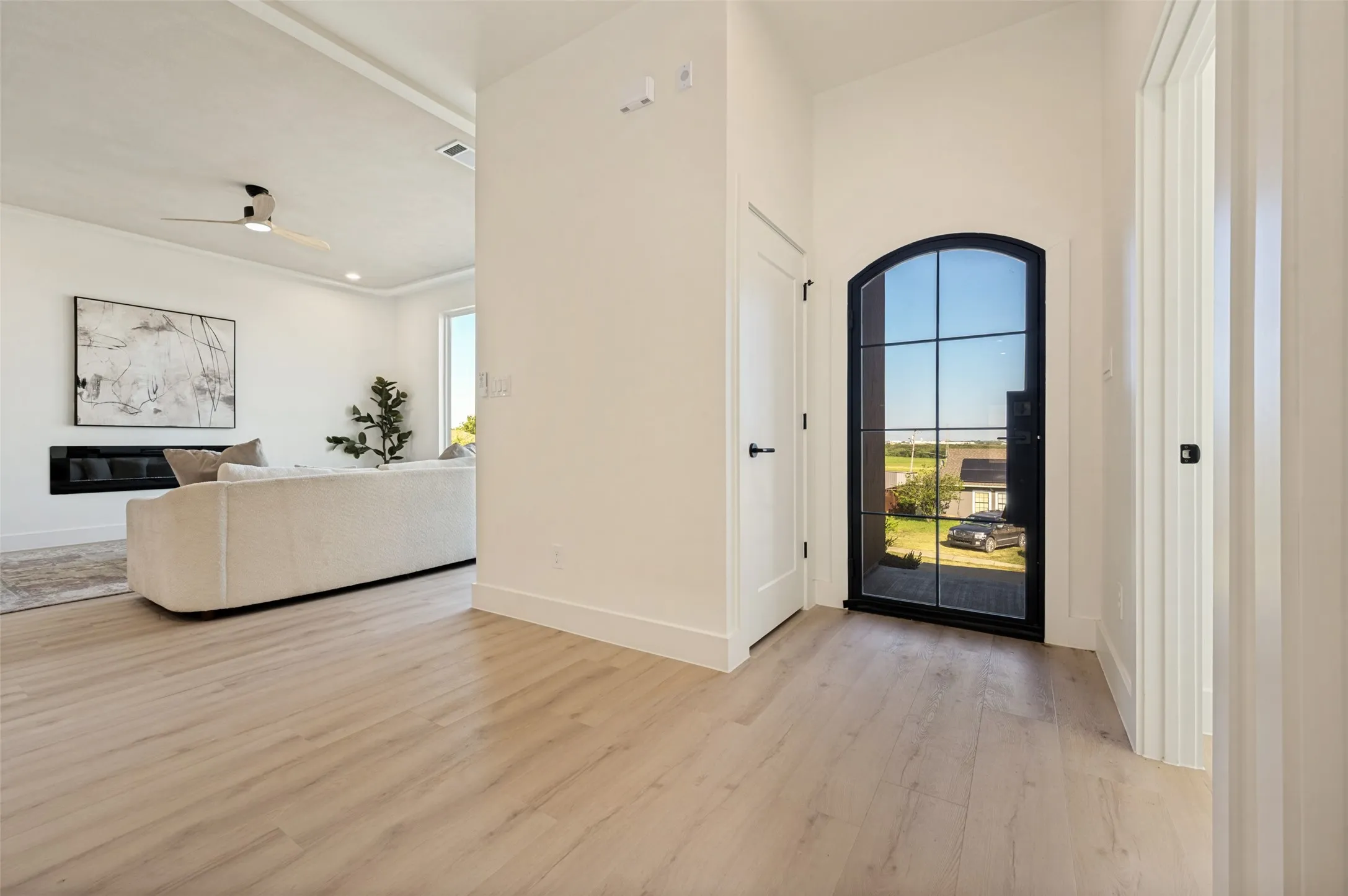Entryway featuring a black-framed arched glass door, light wood-finish flooring, and white baseboards