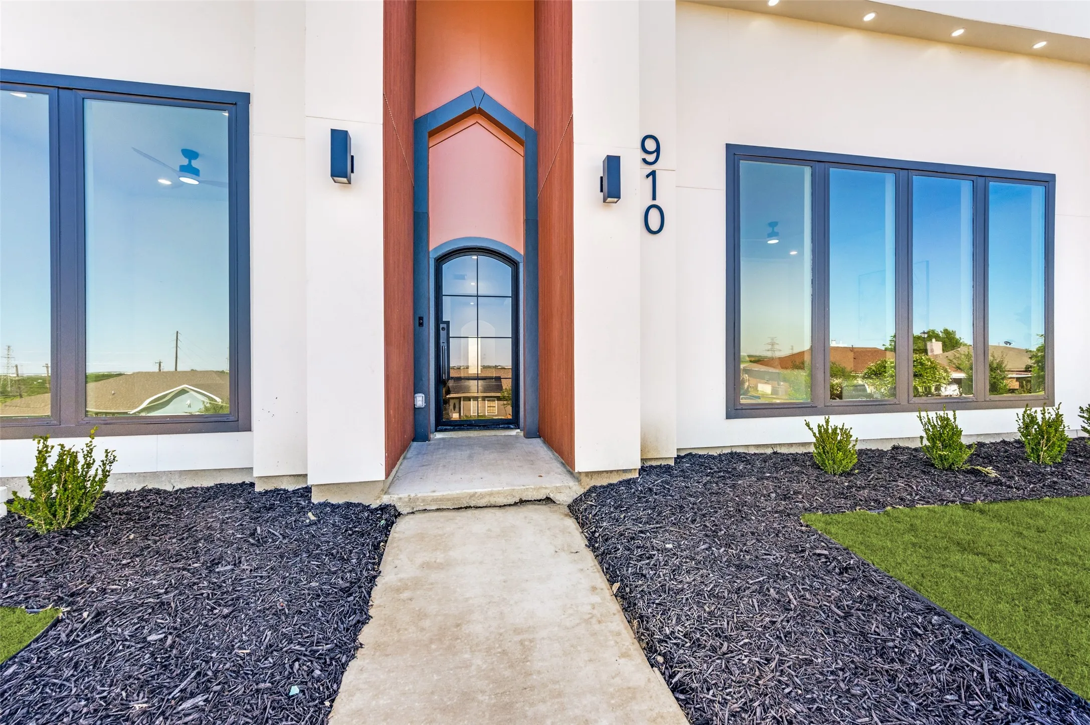 Contemporary exterior with an arched entry door and contrasting accent columns