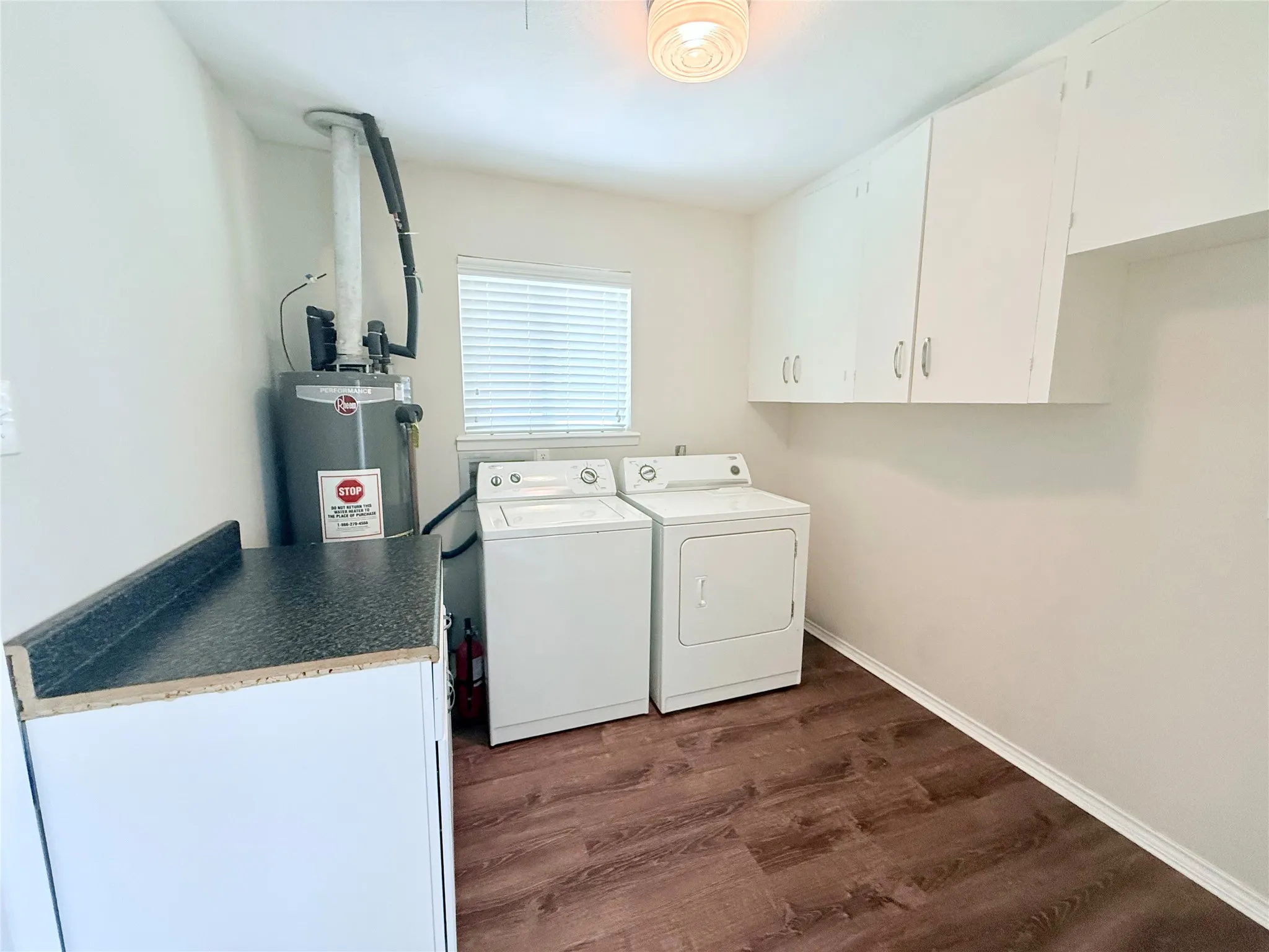Laundry area featuring wood-finish flooring, white cabinetry, and a countertop workspace