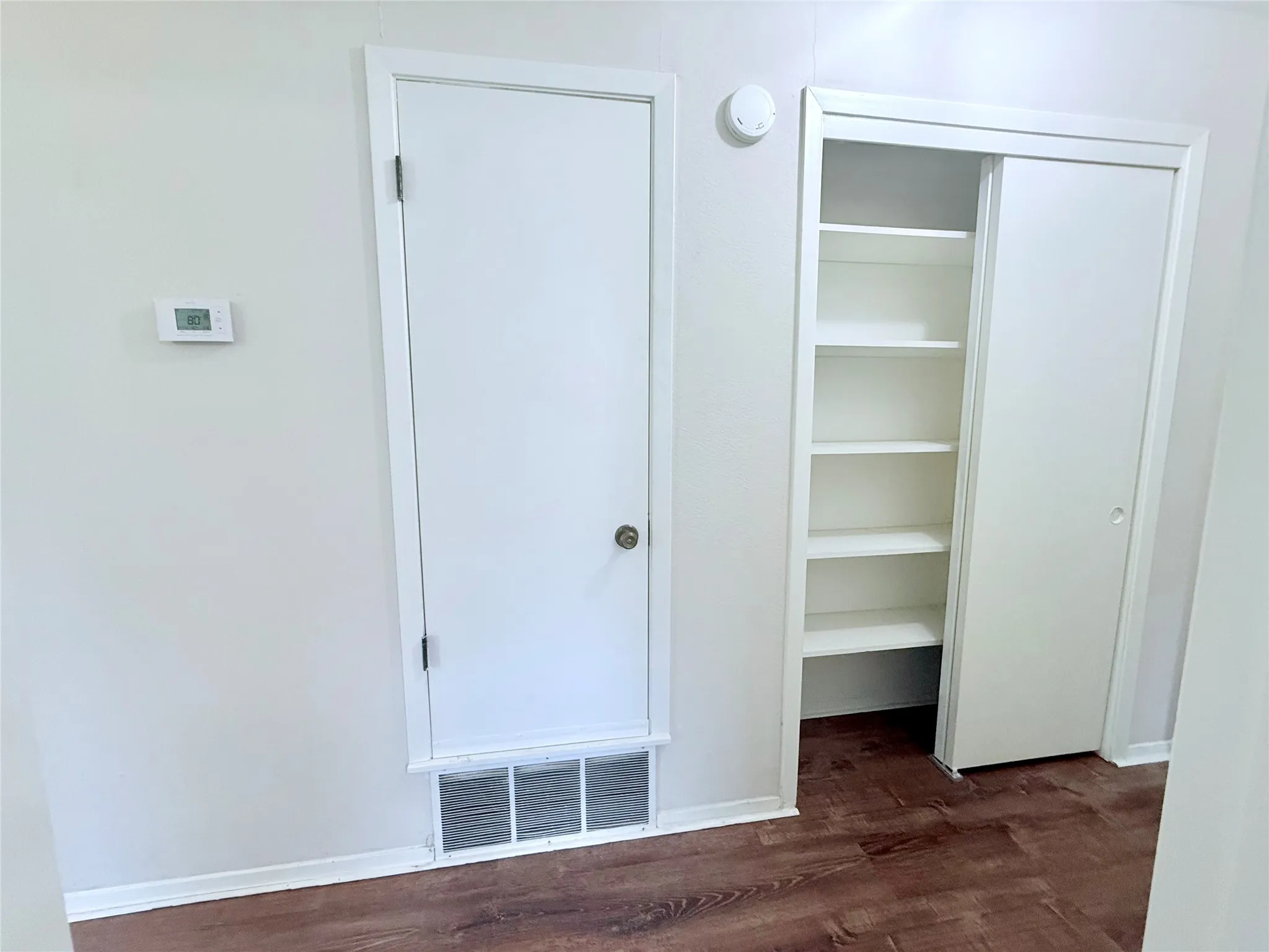 Room featuring wood-finish flooring, white walls, and white baseboards
