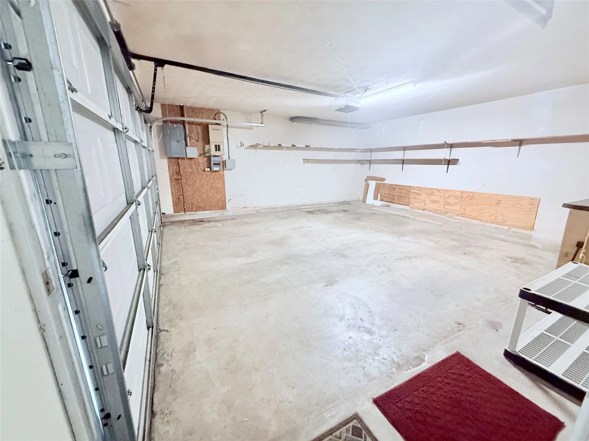 Spacious garage with a concrete floor, overhead lighting, and white panel garage door