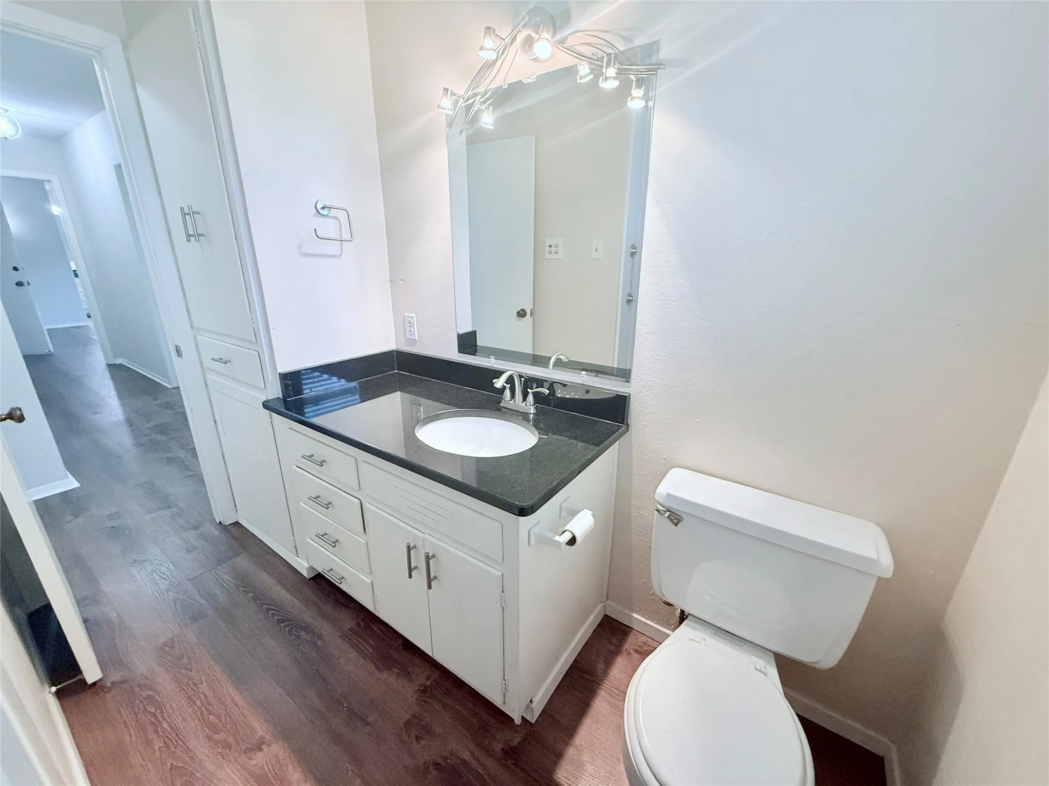 Bathroom featuring a dark countertop vanity with an integrated sink and base cabinetry