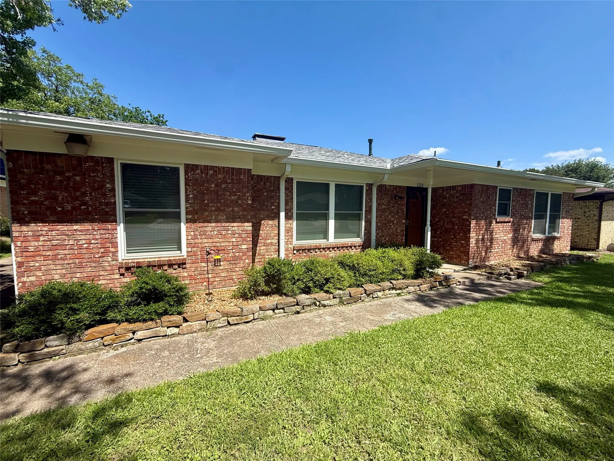 Brick exterior featuring a covered entry and multiple windows