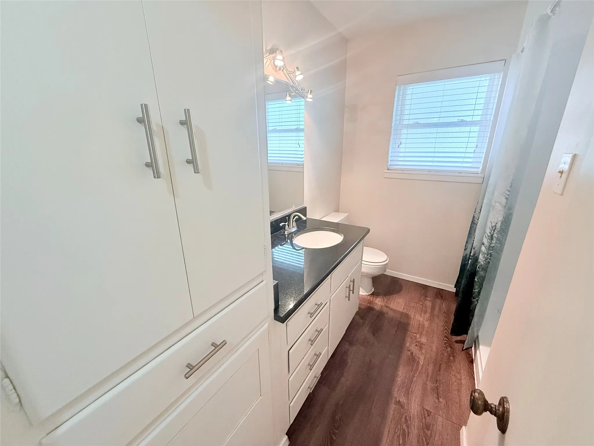 Bathroom featuring a white vanity with a black countertop, integrated sink, and chrome hardware