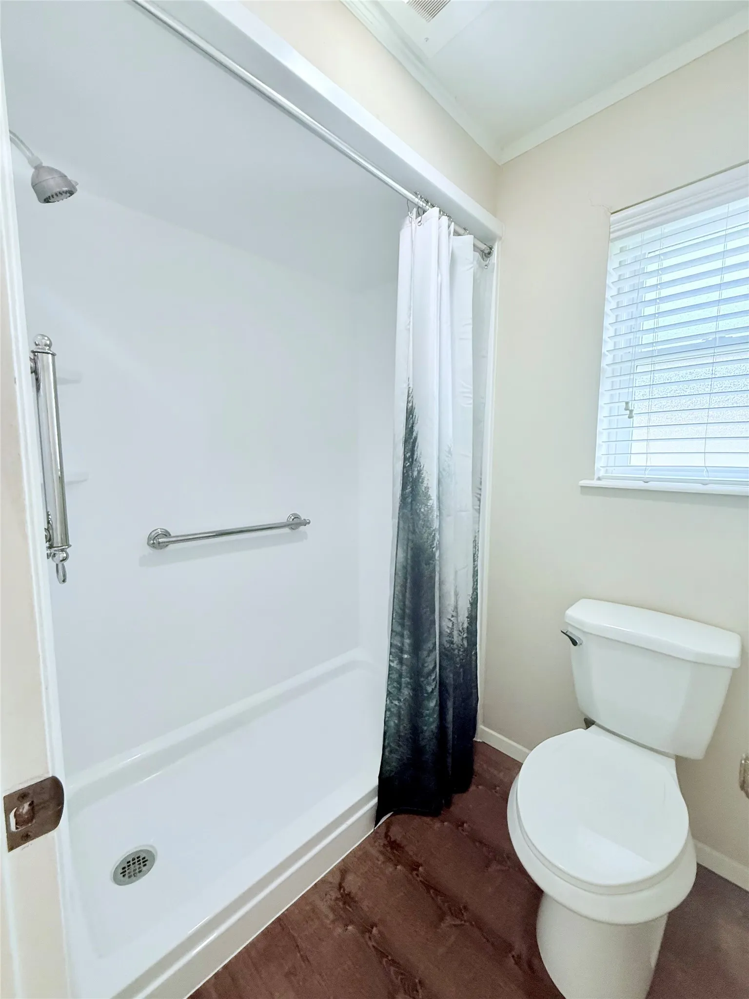 Bathroom featuring a built-in shower with white surround, an integrated grab bar, and a standard toilet
