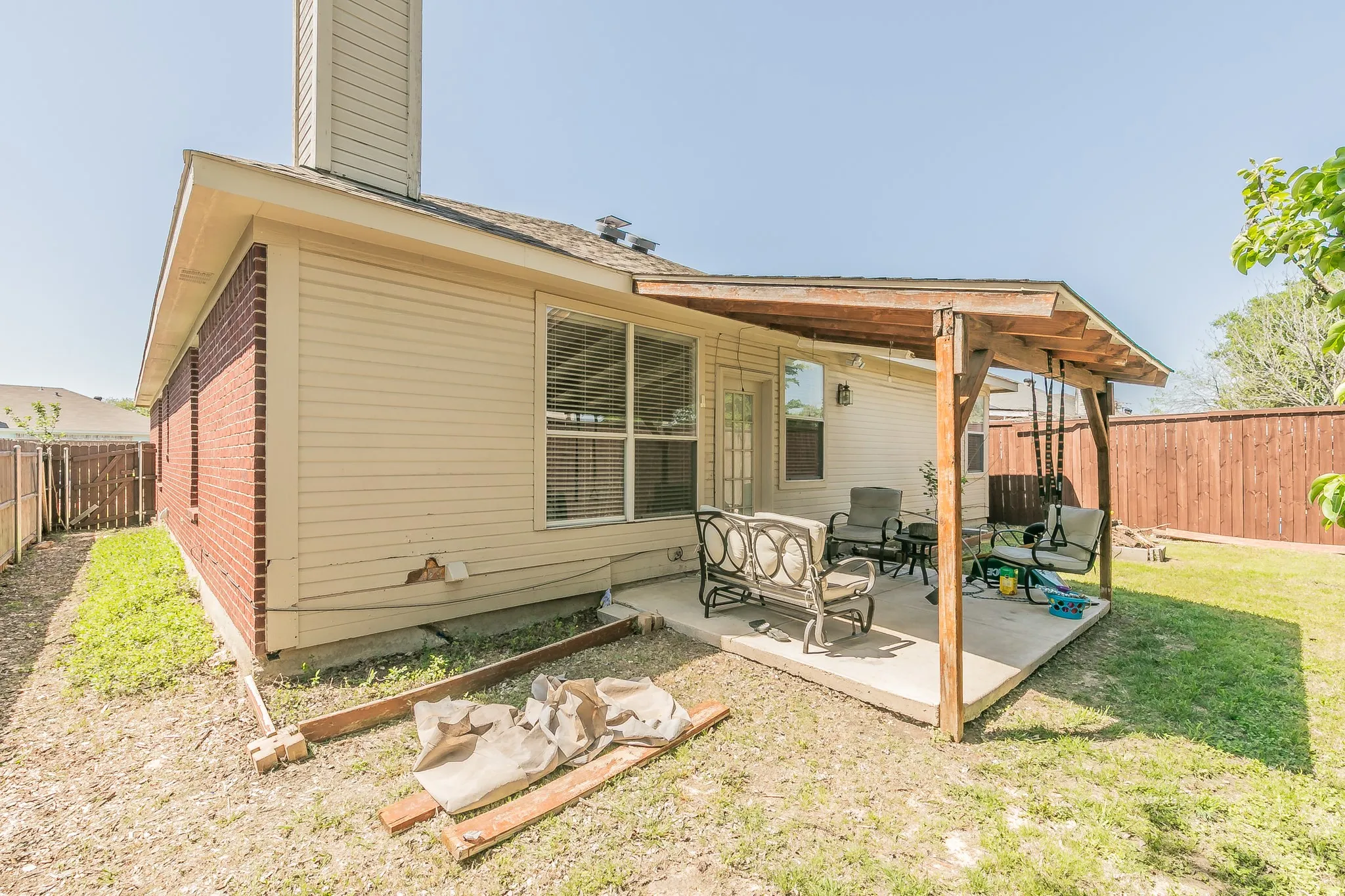 Rear view of property with a fenced backyard, a lawn, a patio area, brick siding, and a chimney