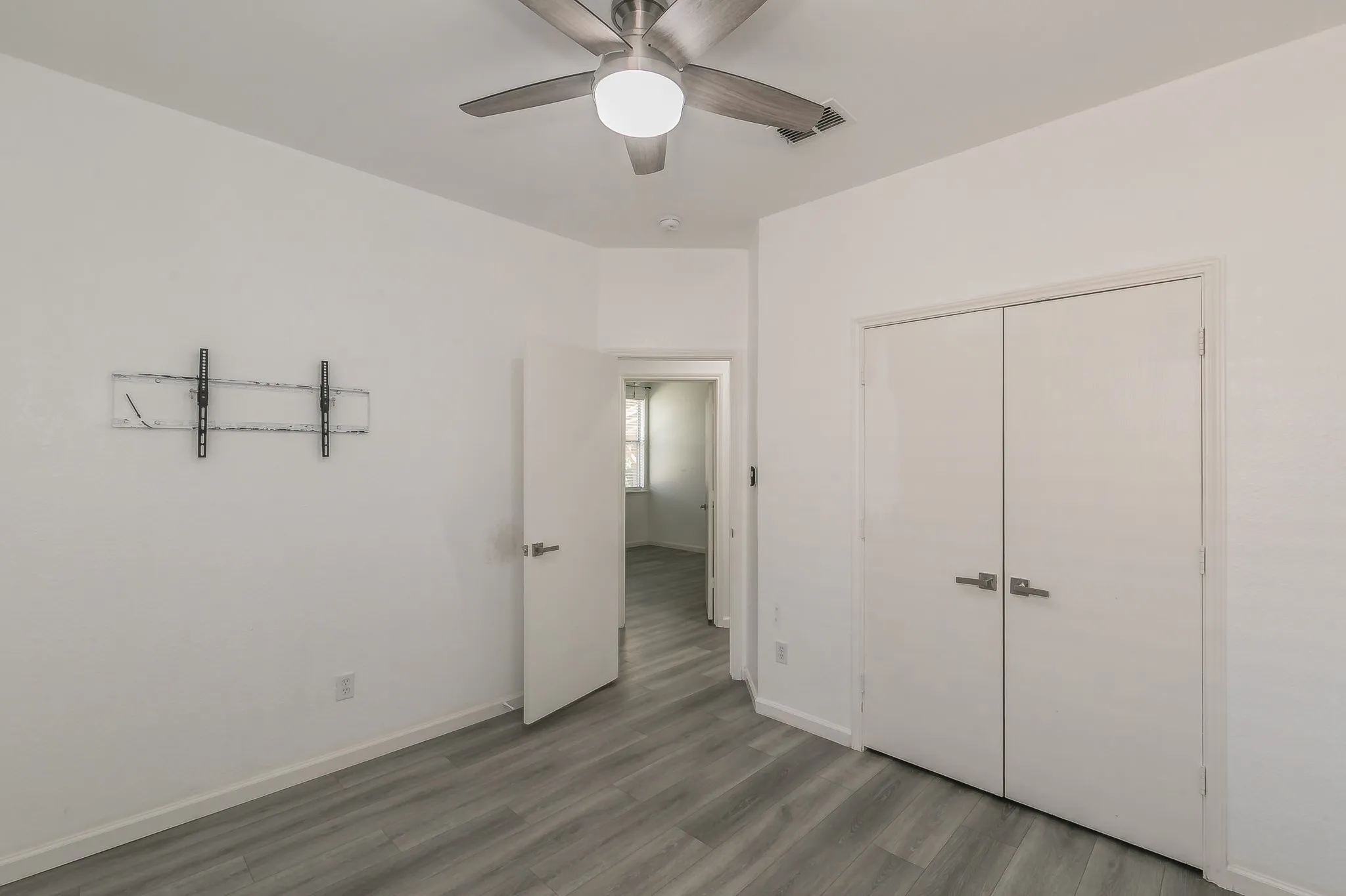 Unfurnished bedroom with ceiling fan, a closet, visible vents, wood finished floors, and baseboards