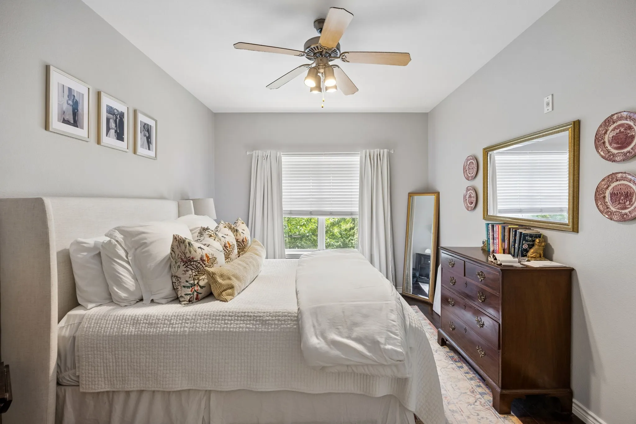 Bright room featuring a single window with blinds, a ceiling fan with integrated lighting, wood-finish flooring, and light gray wall paint