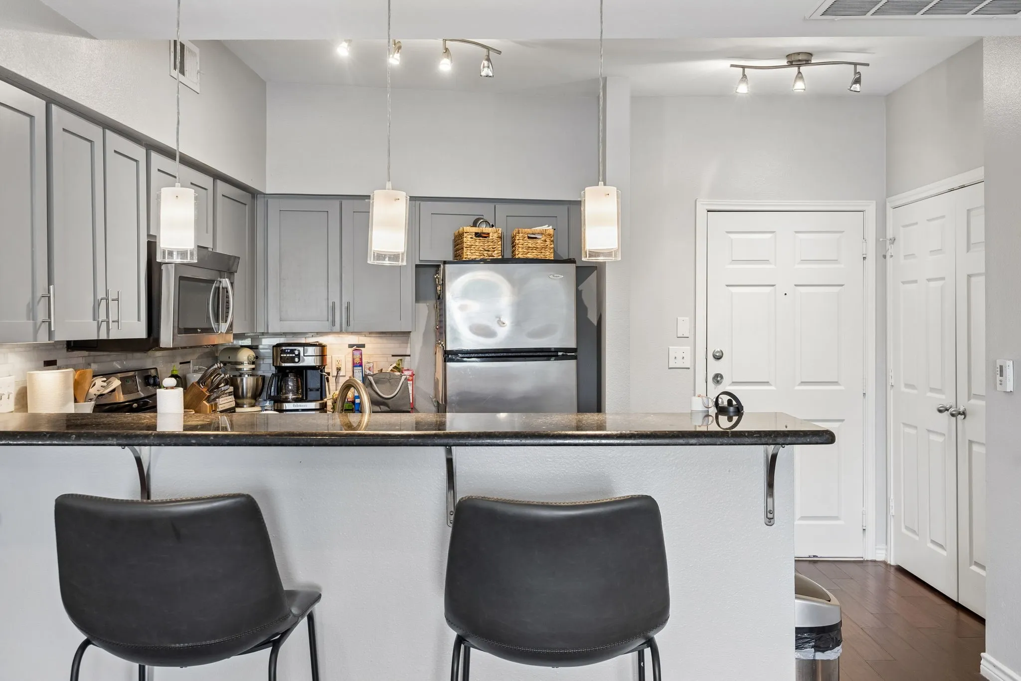 Kitchen featuring gray cabinetry, dark countertops, stainless steel appliances, and integrated bar seating