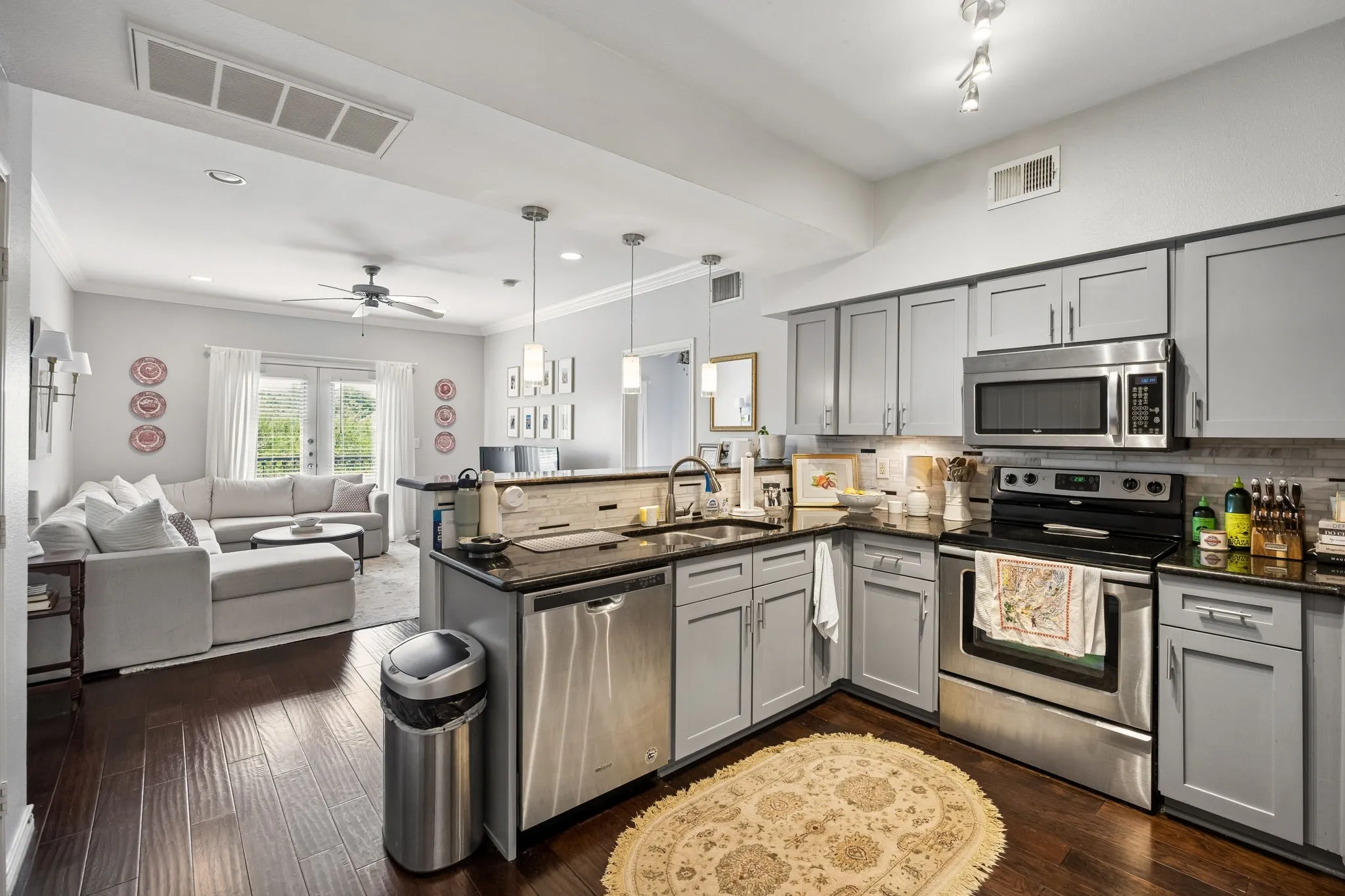 Kitchen featuring grey cabinetry, stainless steel appliances, dark countertops, and a tile backsplash