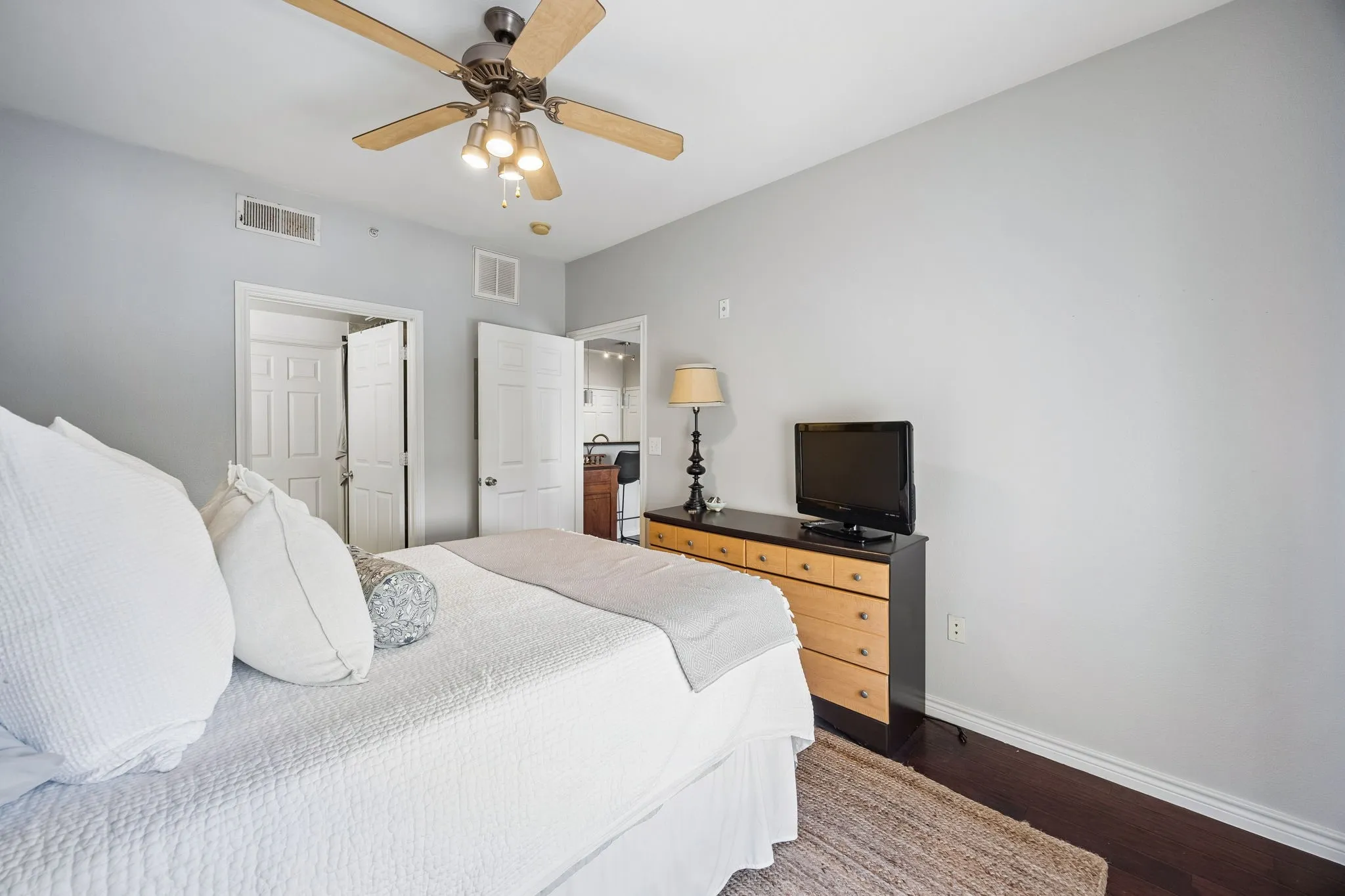 Bedroom with dark wood-finish flooring, light grey walls, and white baseboards