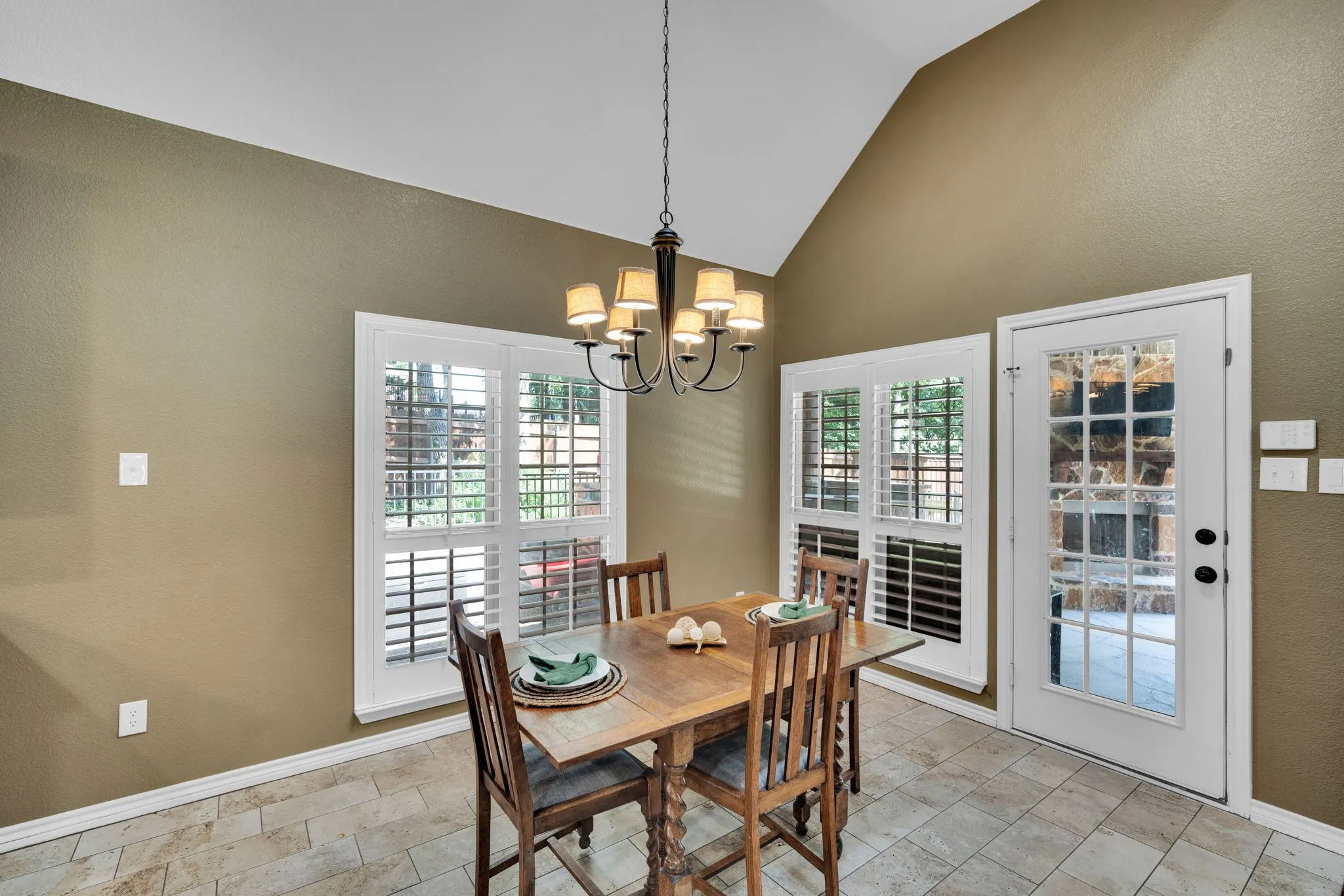 Bright informal dining area with a vaulted ceiling and French doors leading outside.