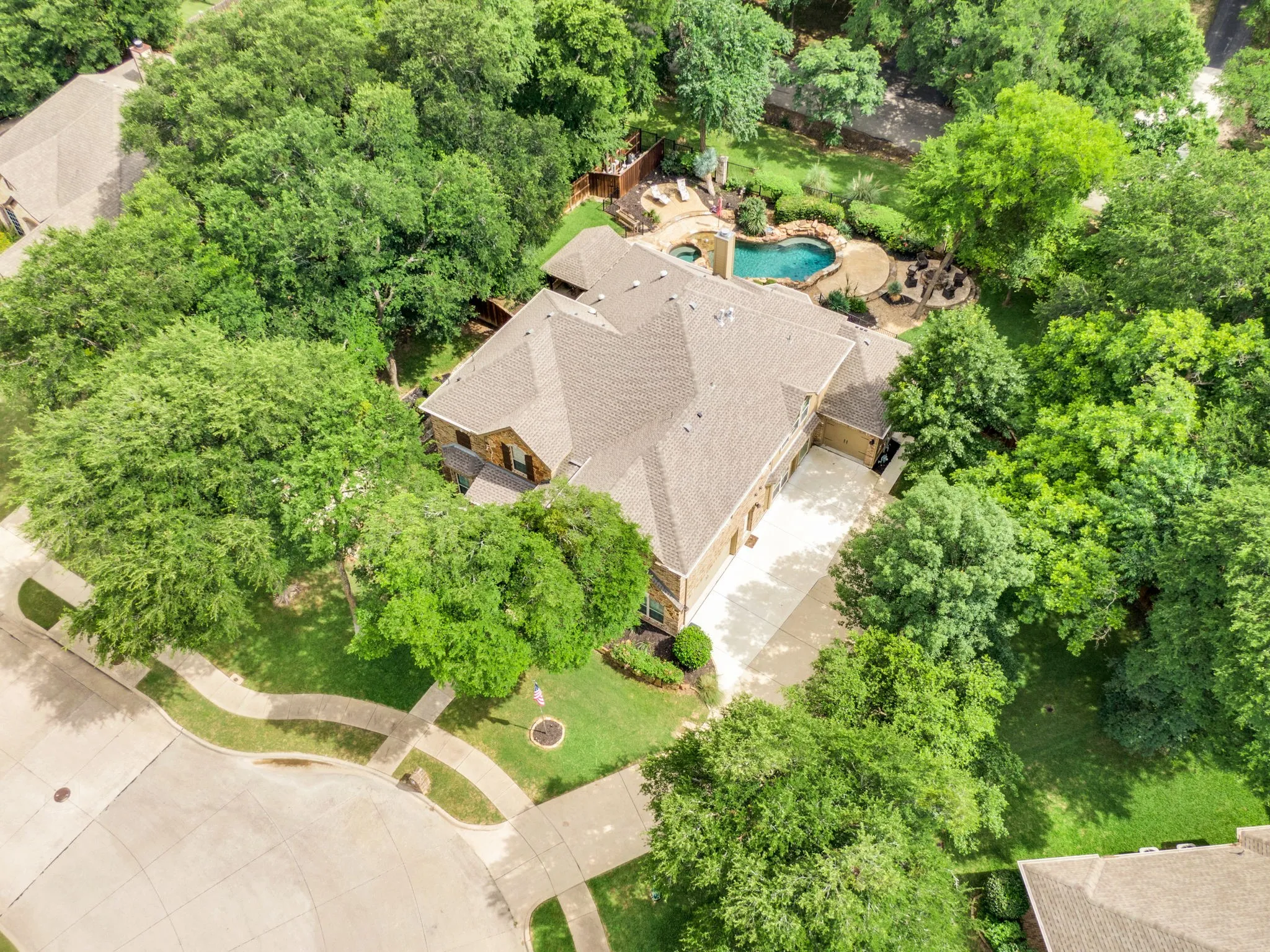 Aerial view showcasing the home's wooded lot and sparkling pool.