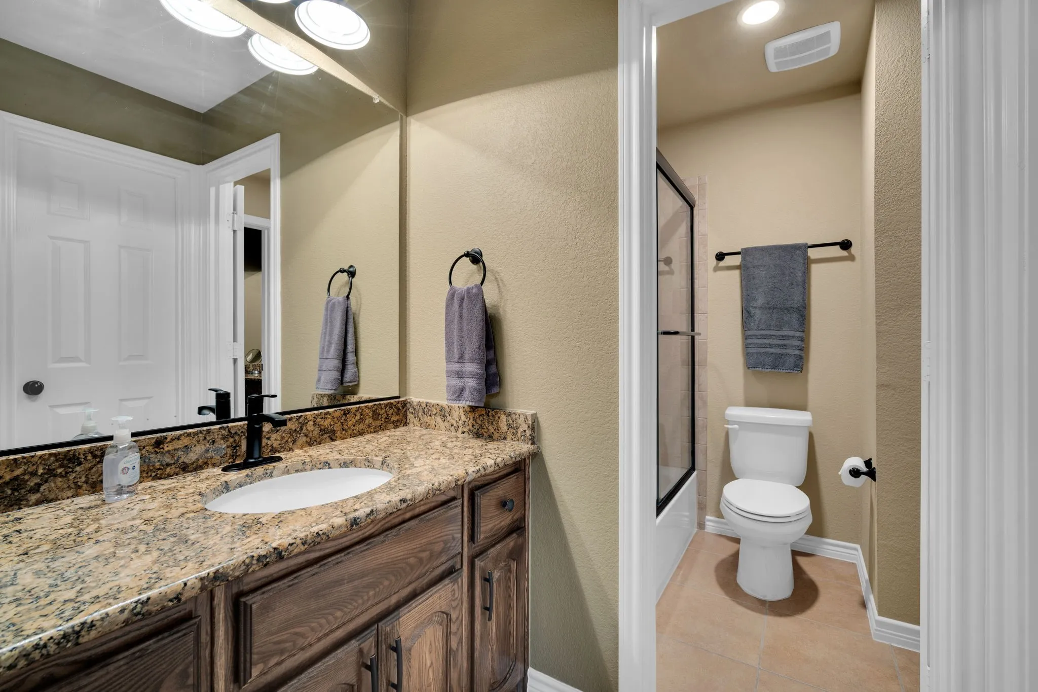 Secondary bathroom with a granite vanity and a separate water closet.