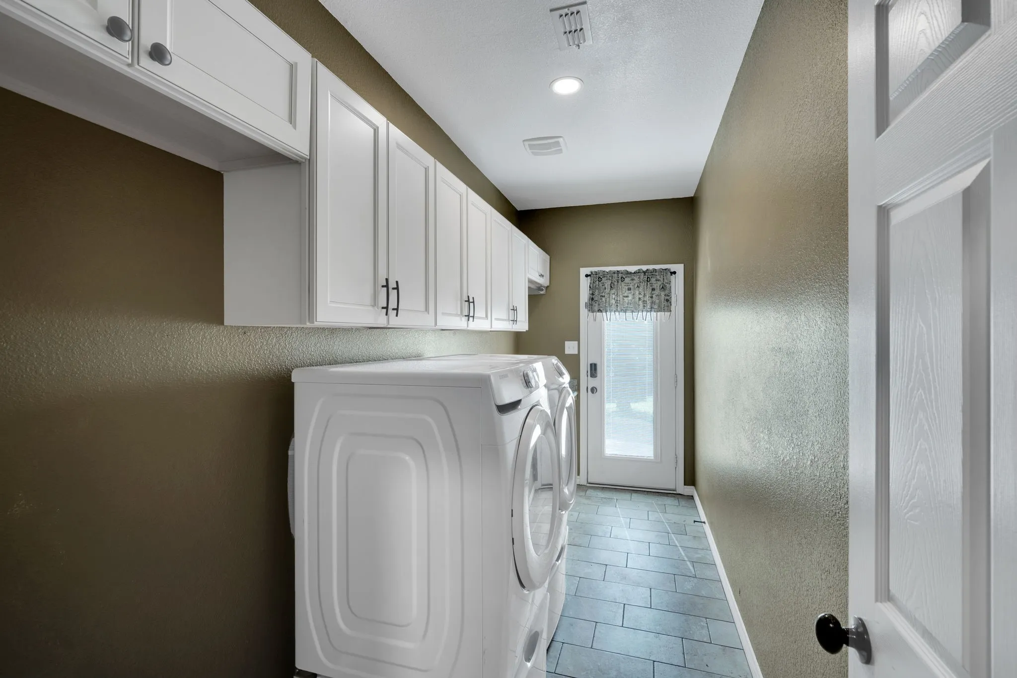 Laundry room with generous cabinetry and counter space.