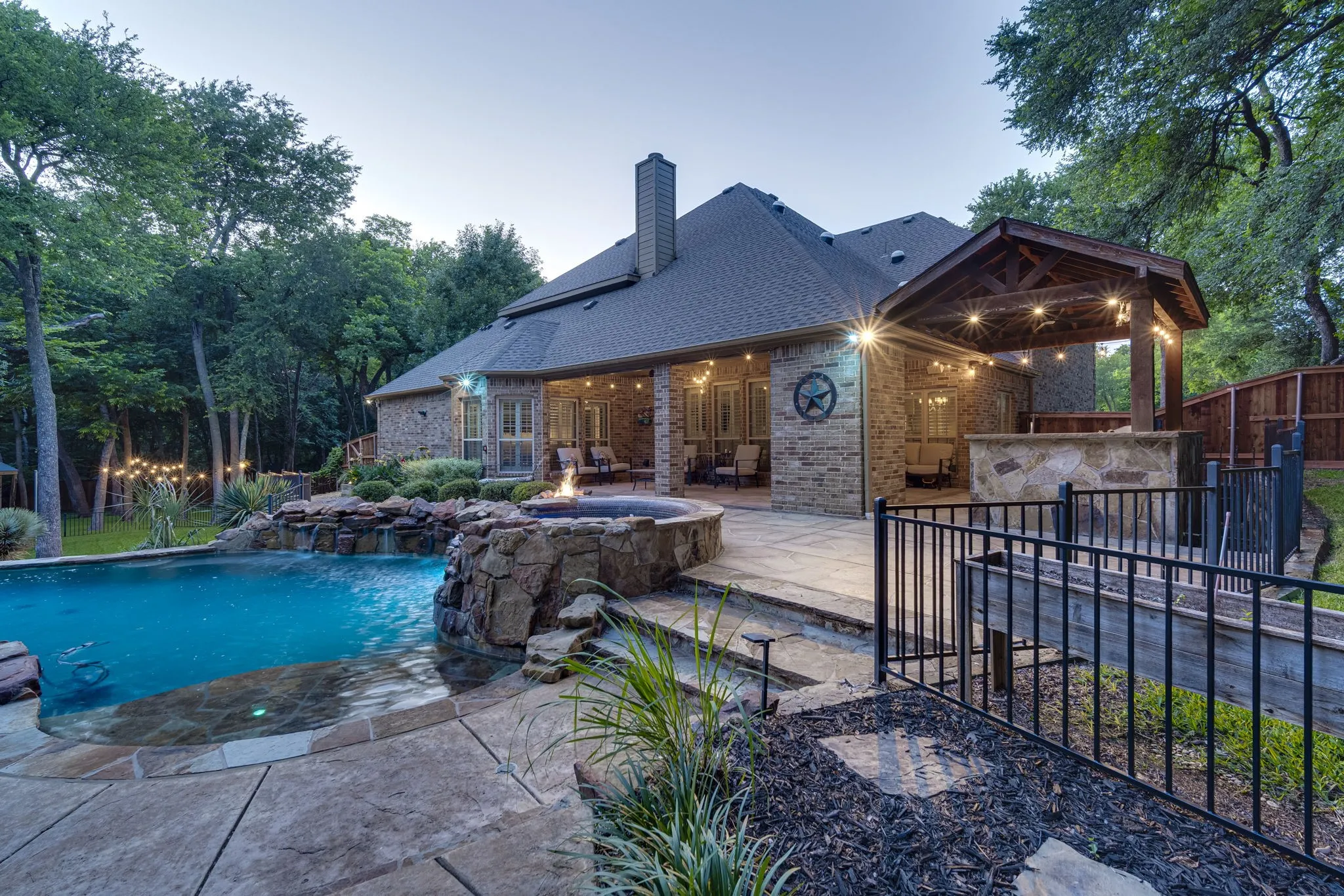 Breathtaking backyard oasis combining a sparkling pool, covered patio, and stone fireplace for year-round enjoyment.