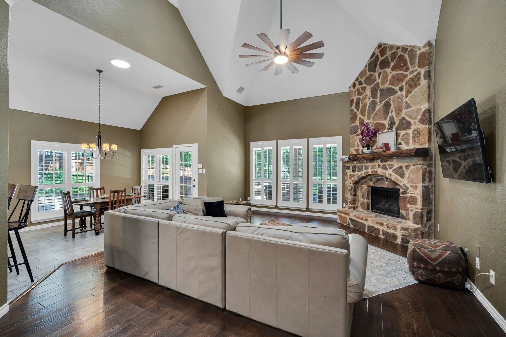 Living room with soaring vaulted ceilings, a stone fireplace, and French doors opening to the backyard oasis.