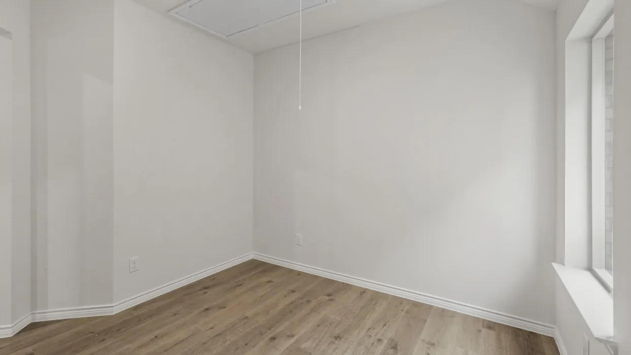 Light-filled room featuring wood-finish flooring, white baseboards, and a window with a deep sill