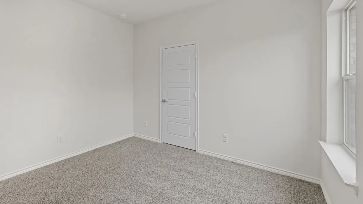 Neutral white wall paint, gray carpeting, and a white interior door with horizontal paneling