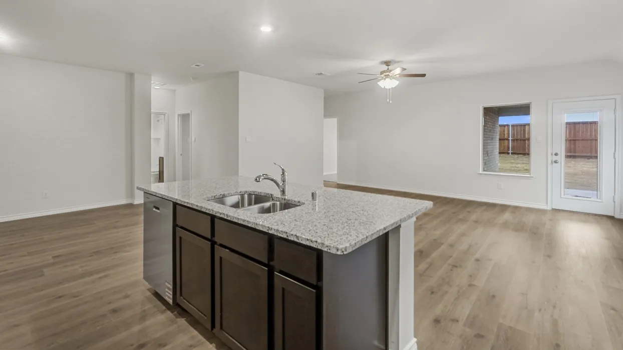 Kitchen island featuring a double-basin sink, stainless steel faucet, and integrated dishwasher