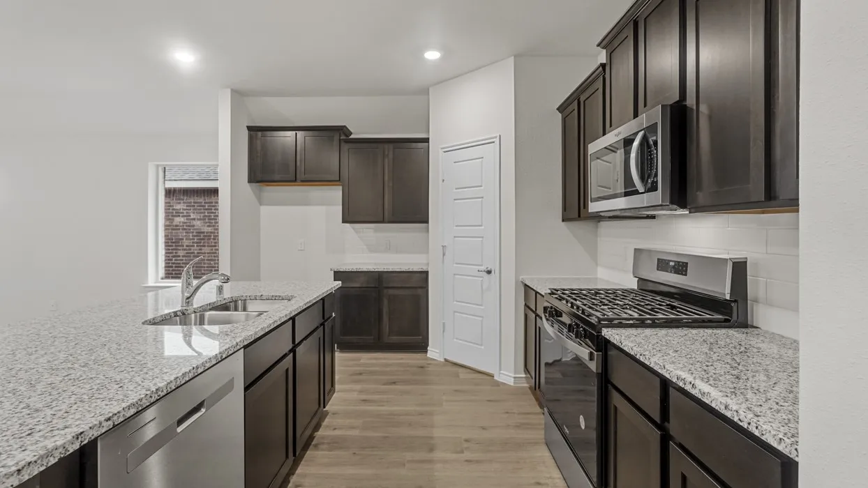 Kitchen featuring granite countertops, wood-finish flooring, dark wood cabinetry, stainless steel appliances, and a subway tile backsplash