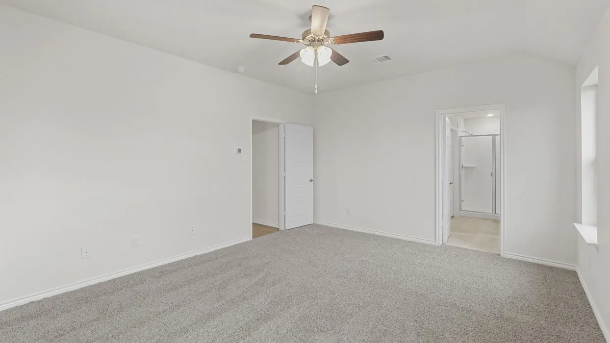 Spacious room featuring vaulted ceilings, light gray carpeting, and a ceiling fan with integrated lighting