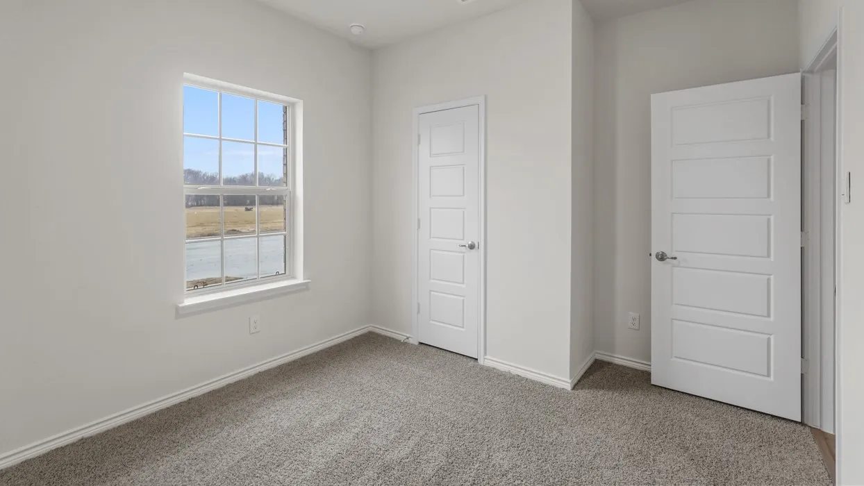 Room featuring neutral wall paint, gray carpet flooring, a large window with white trim, and two white five-panel interior doors