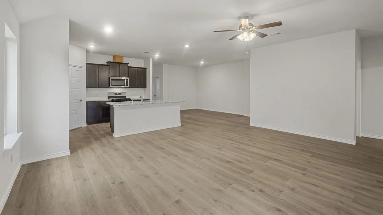 Spacious open-concept living area featuring wood-finish flooring, recessed lighting, and a ceiling fan