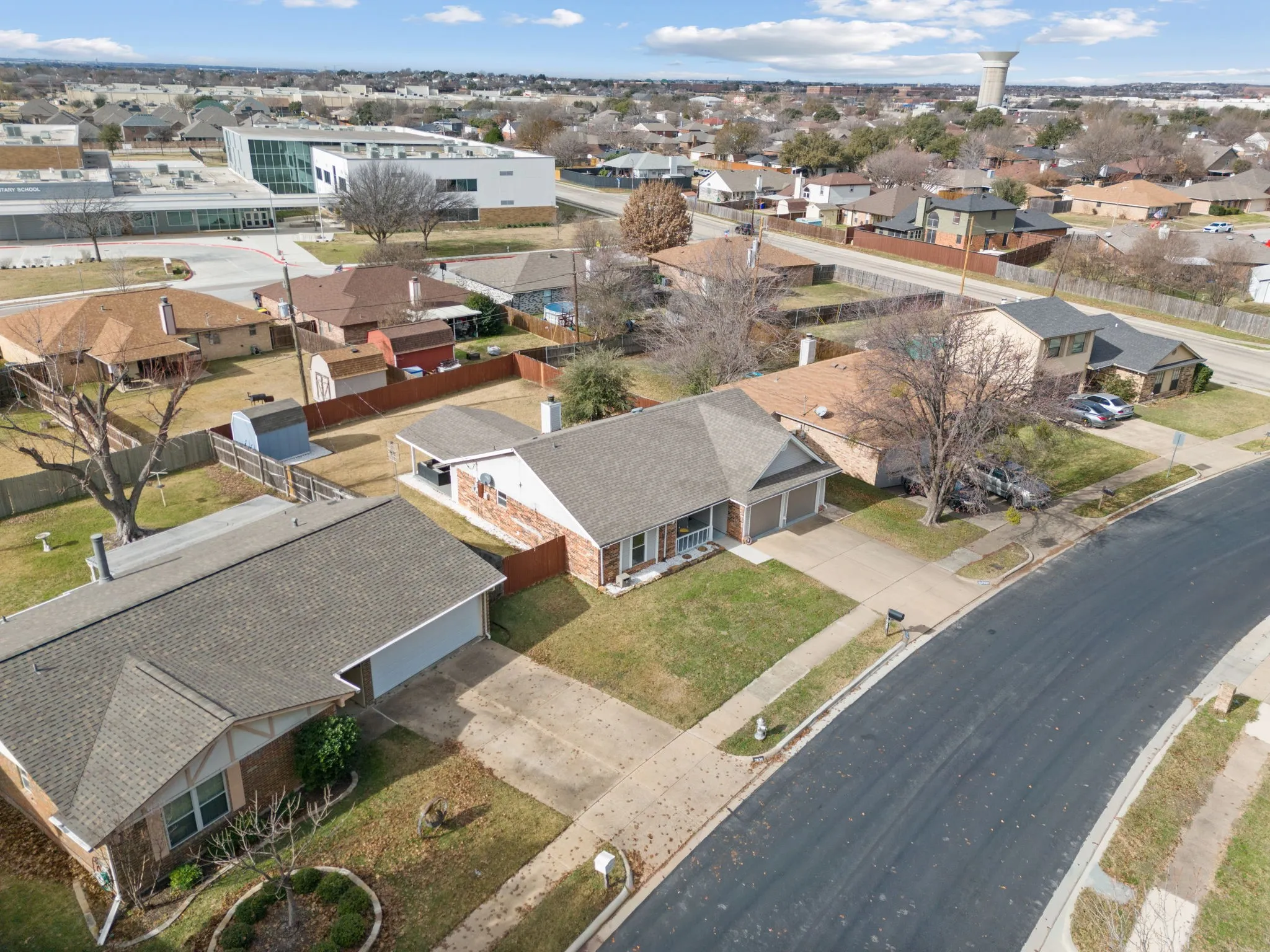 Aerial perspective showcasing a residential neighborhood with single-story homes, asphalt streets, and mature trees