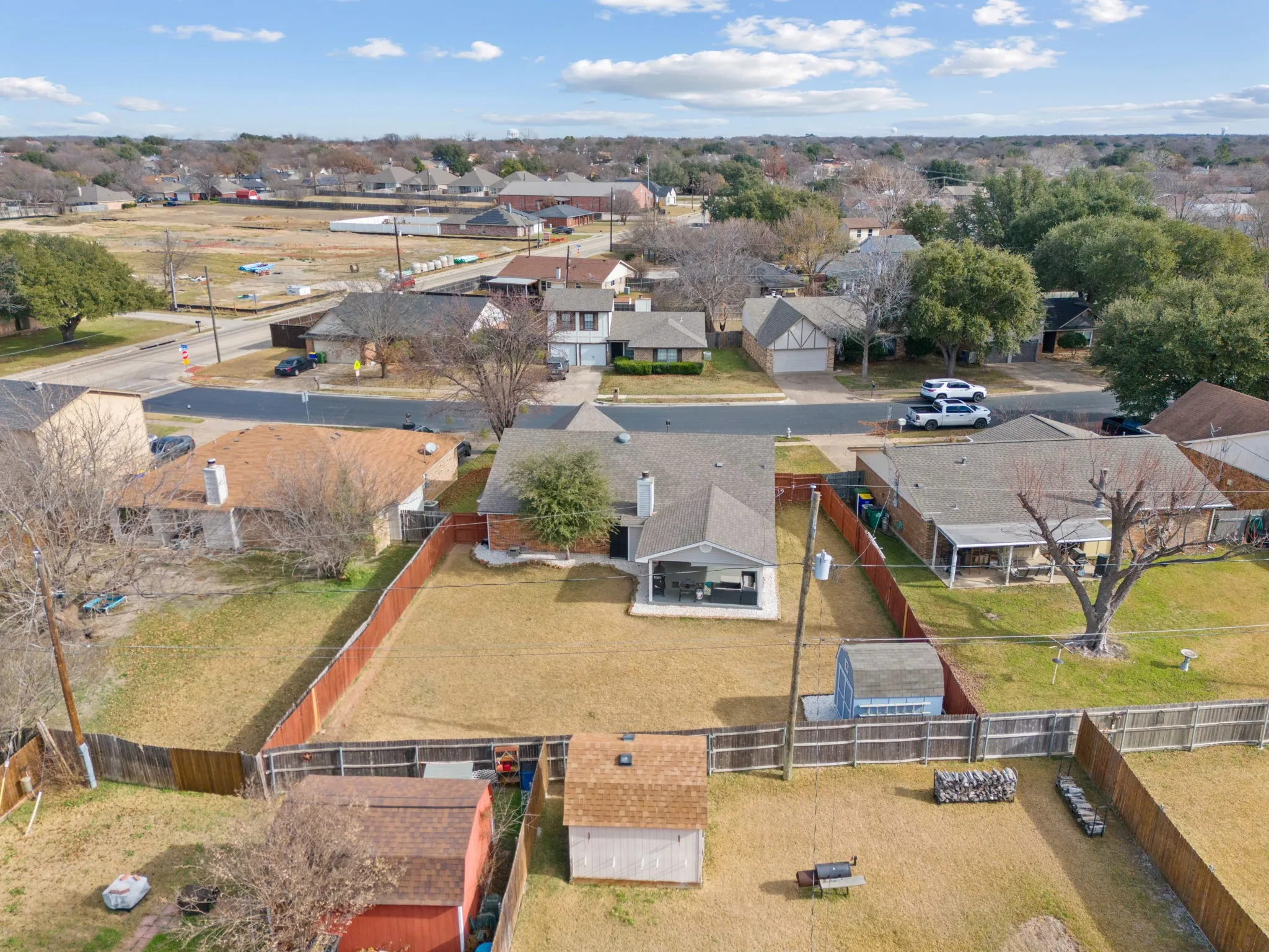 Expansive backyard featuring a wood fence, multiple storage sheds, and mature landscaping